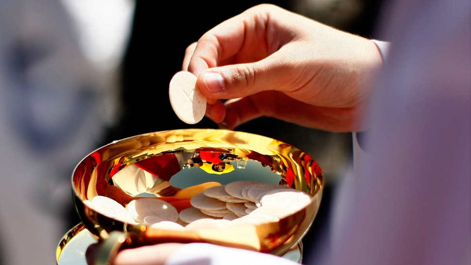 A priest holds a Holy Communion wafer as Pope Benedict XVI celebrates Mass at Nationals Park April 17, 2008 in Washington, DC.