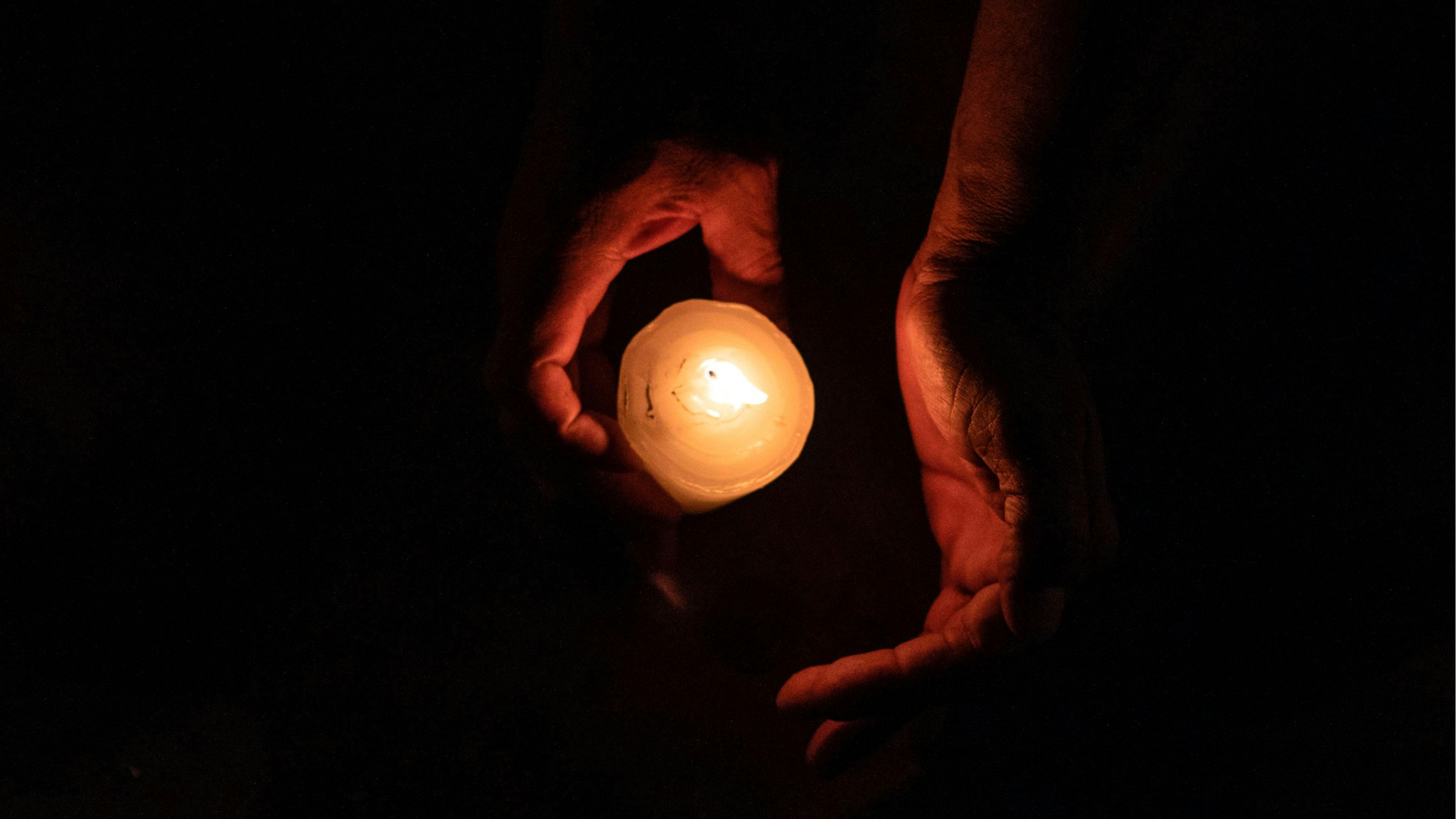 A member of the Pueblos Sin Fronteras, a pro-immigration advocacy group, lights a candle during a vigil to raise awareness of local police harassment and abuse of migrants, deported migrants and homeless in Tijuana, Baja California state, on September 16, 2018.
