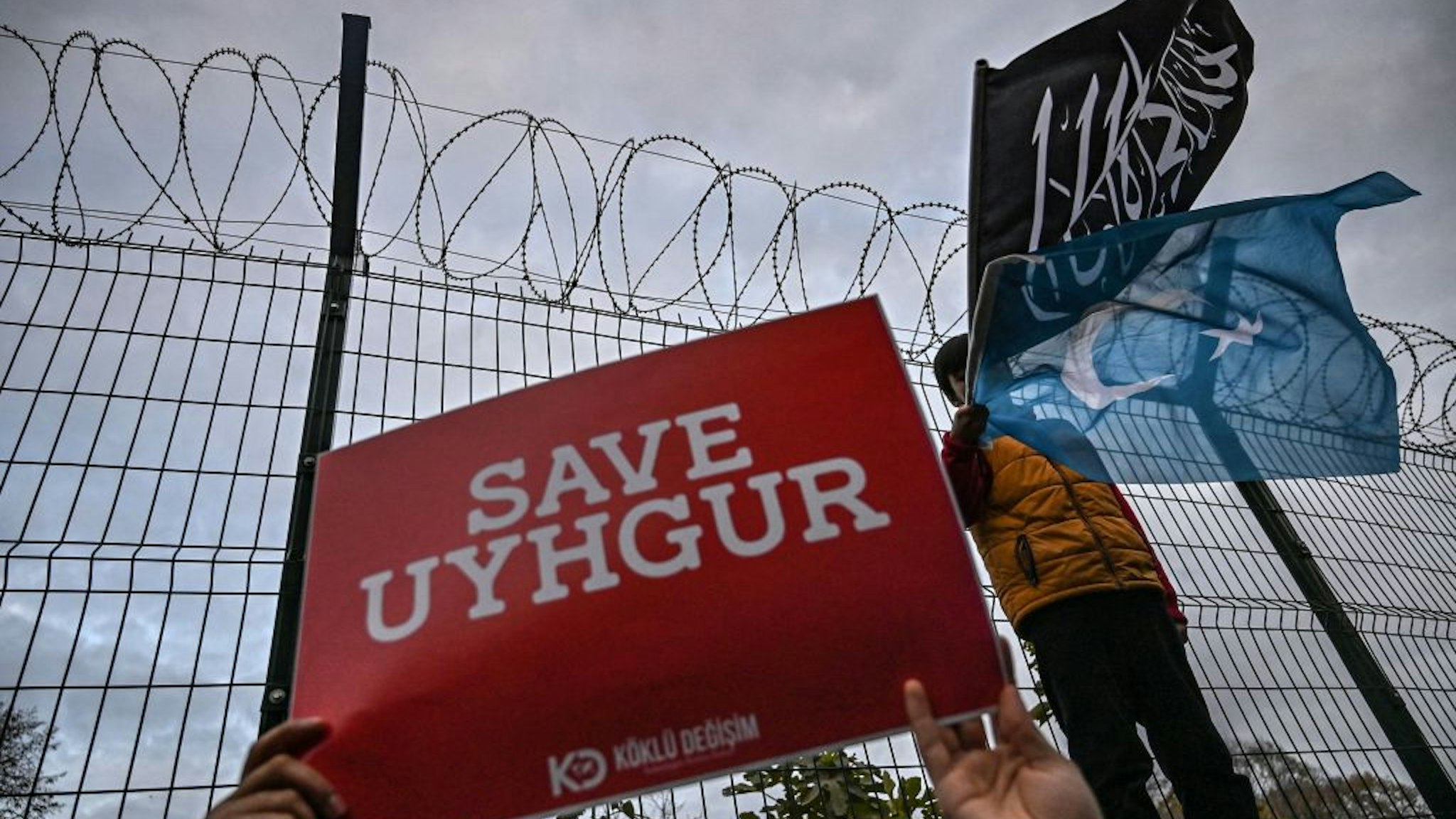A supporters of China's Muslim Uighur minority holds a placard reading "Save Uighur" as a boy waves the flag of East Turkestan and an Islamic black flag on December 13, 2019 during a demostration in front of China Consulate in Istanbul.