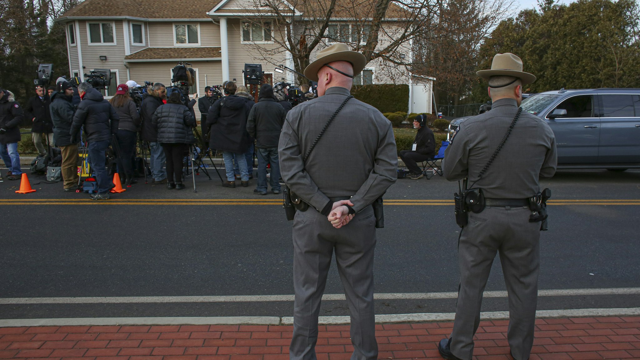 Two police officers stand guard as the press gathers outside a rabbi's home where a machete attack that took place earlier during the Jewish festival of Hanukkah, in Monsey, New York, on December 29, 2019. - An intruder stabbed and wounded five people at a rabbi's house in New York during a gathering to celebrate the Jewish festival of Hanukkah late on December 28, 2019, officials and media reports said. Local police departments, speaking to AFP, declined to give the number of people injured, but a suspect has been taken into custody and a vehicle safeguarded, an NYPD spokesman said. (Photo by Kena Betancur / AFP) (Photo by KENA BETANCUR/AFP via Getty Images)