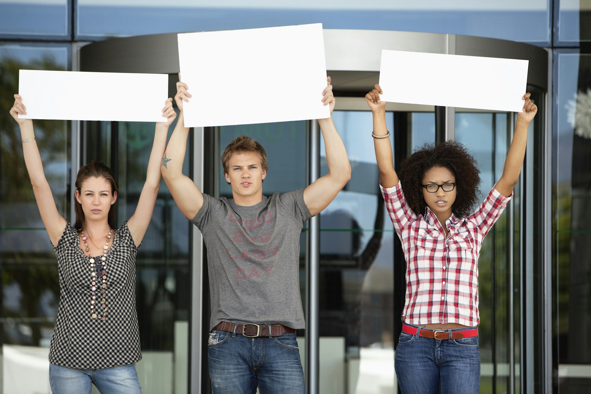Three friends protesting with blank placards - stock photo