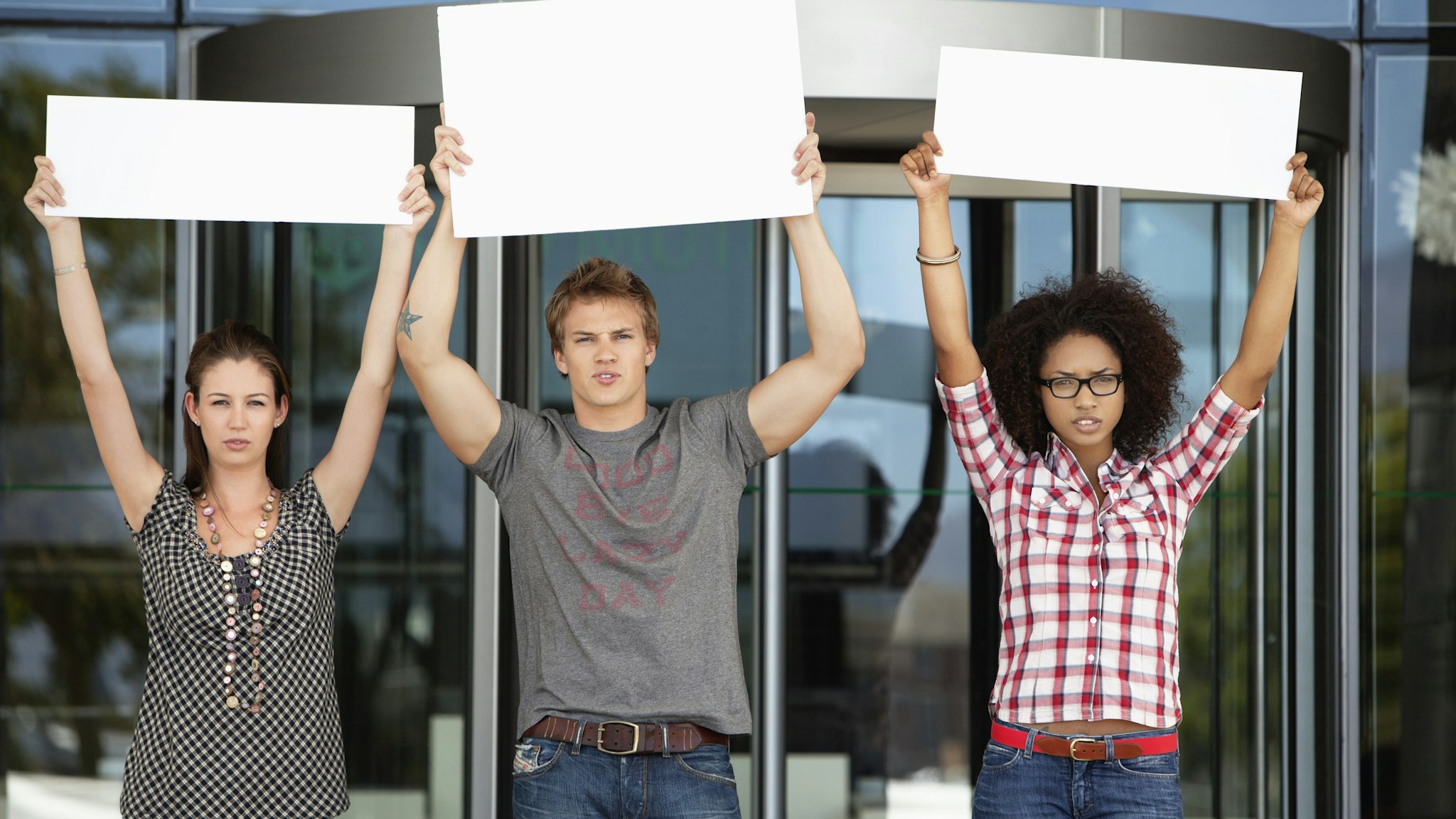 Three friends protesting with blank placards - stock photo