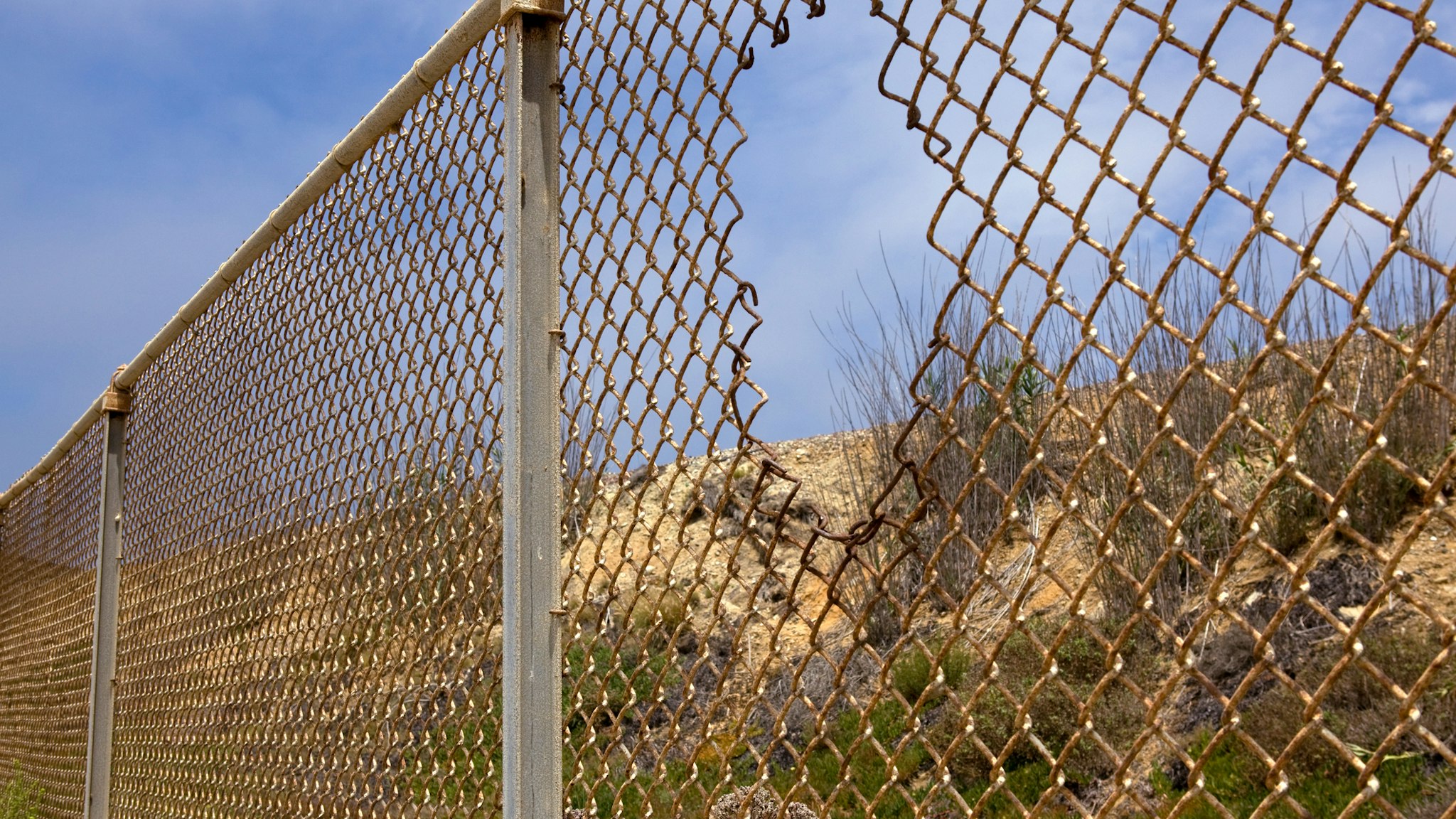 Fence with hole in California desert.