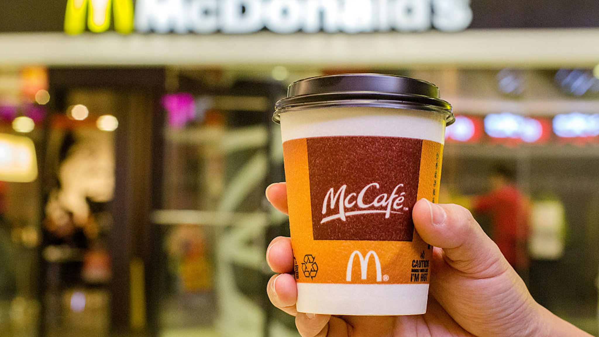 A customer holds a cup of Coffee served by McCafe out of a McDonald's restaurant.