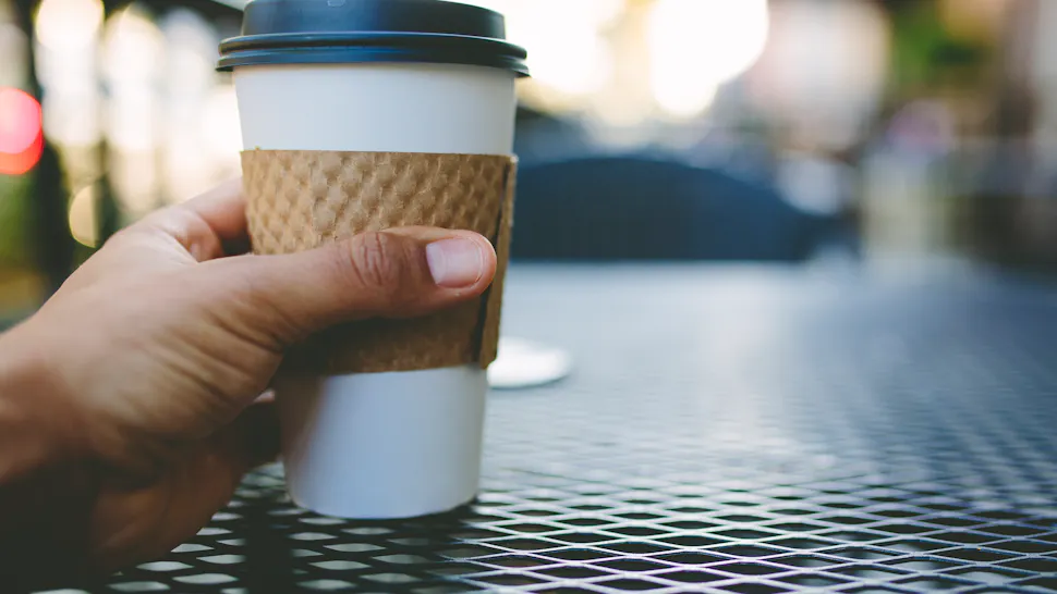 Coffee Point of View A point of view shot holding a necessary morning breakfast item coffee in a to go cup with a blurred sunrise in the background.
