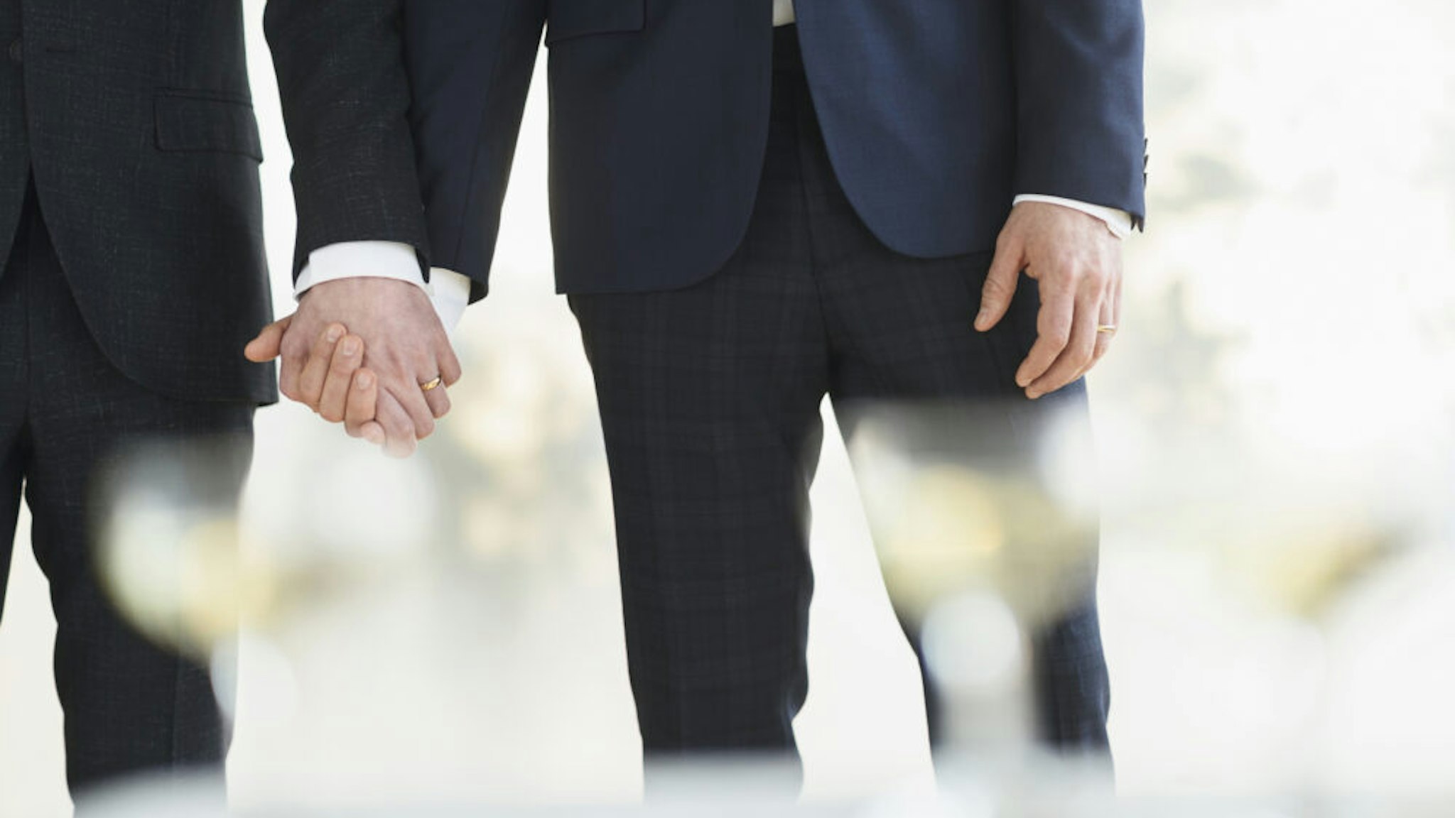 Caucasian gay grooms holding hands at wedding - stock photo