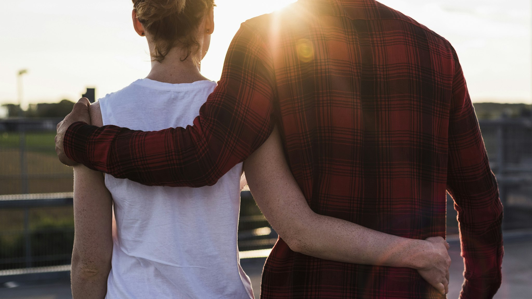 Young couple arm in arm at sunset - stock photo