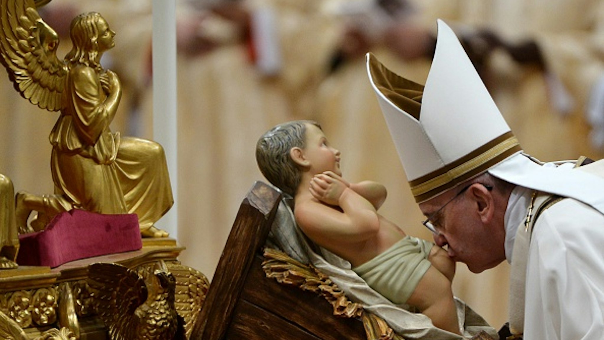 Pope Francis kisses the unveiled baby Jesus during a Christmas Eve mass at St Peter's Basilica to mark the nativity of Jesus Christ, on December 24, 2014 at the Vatican.