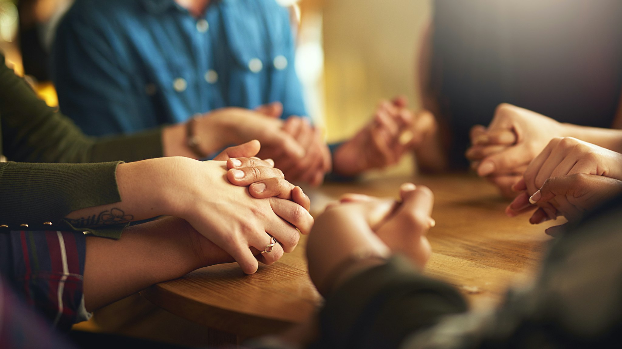 Shot of a group of people holding hands and praying together