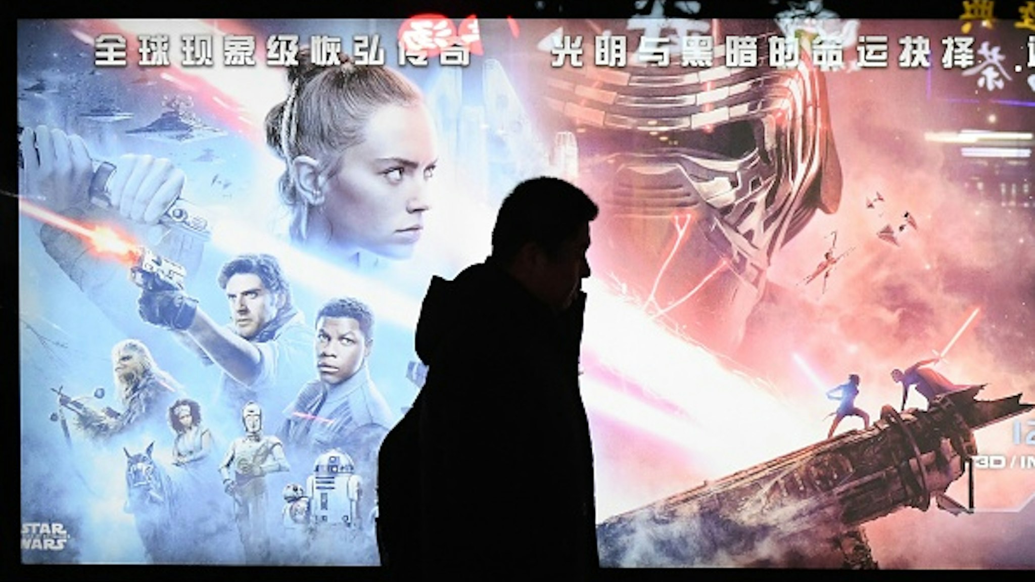 This photo taken on December 19, 2019 shows a man walking past a poster for the latest Star Wars movie, "The Rise of Skywalker", in Beijing. - The movie opens in theaters in China on December 20.