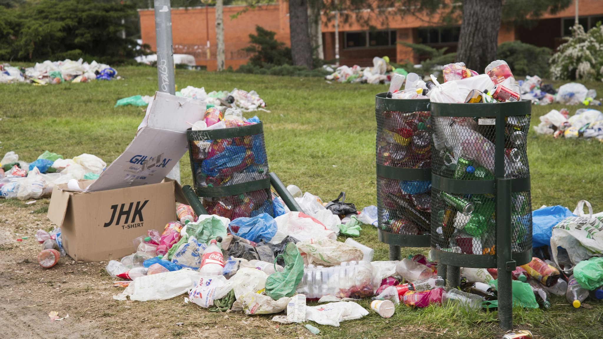 Garbage cans surrounded by plastic containers and glass bottles after a street drinking party (called in Spanish 'botellón') in a green area of Ciudad Universitaria Campus, Complutense University, Madrid, Spain.