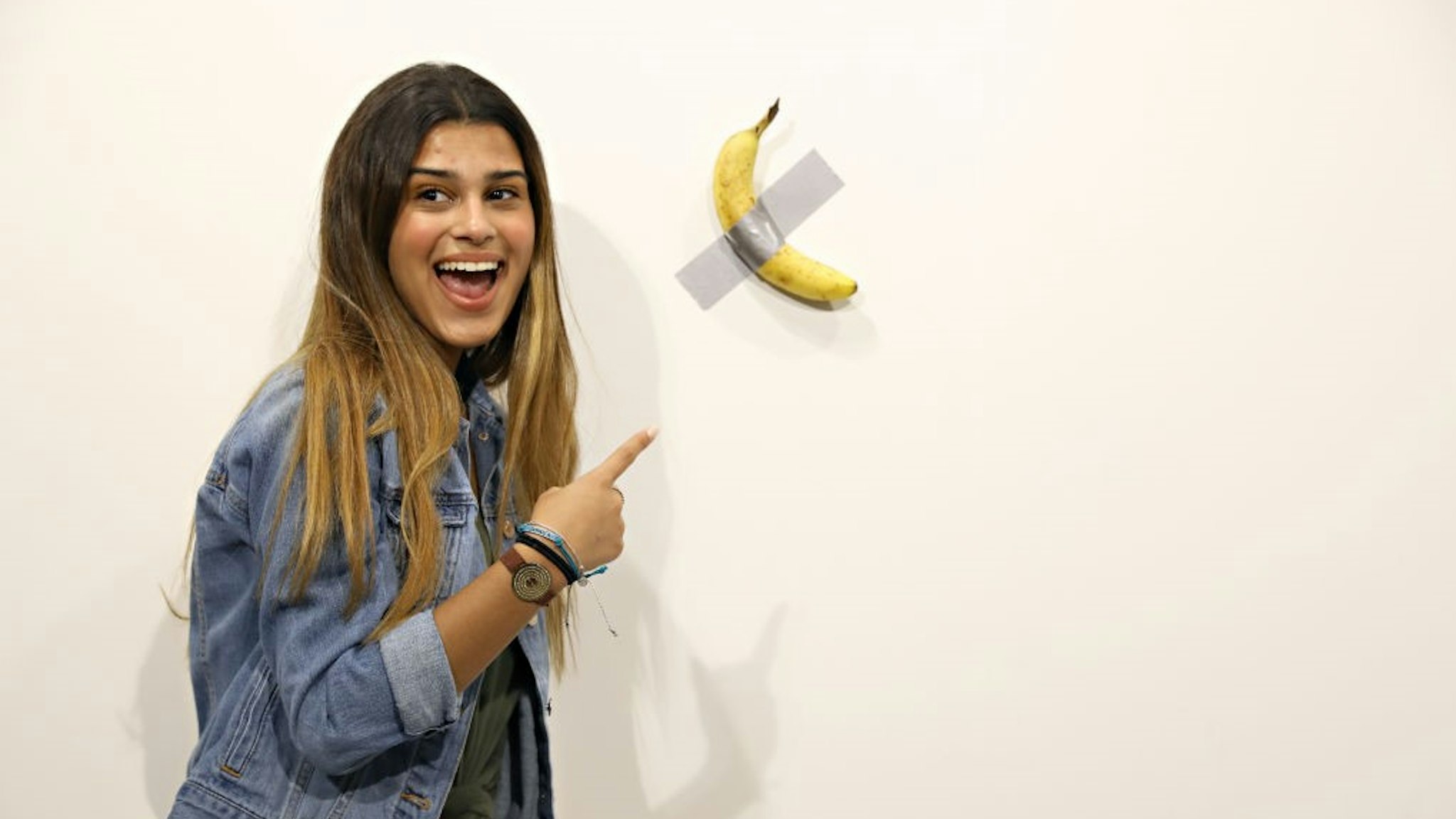 People post in front of Maurizio Cattelan's "Comedian" presented by Perrotin Gallery and on view at Art Basel Miami 2019 at Miami Beach Convention Center on December 6, 2019 in Miami Beach, Florida. Two of the three editions of the piece, which feature a banana duct-taped to a wall, have reportedly sold for $120,000.