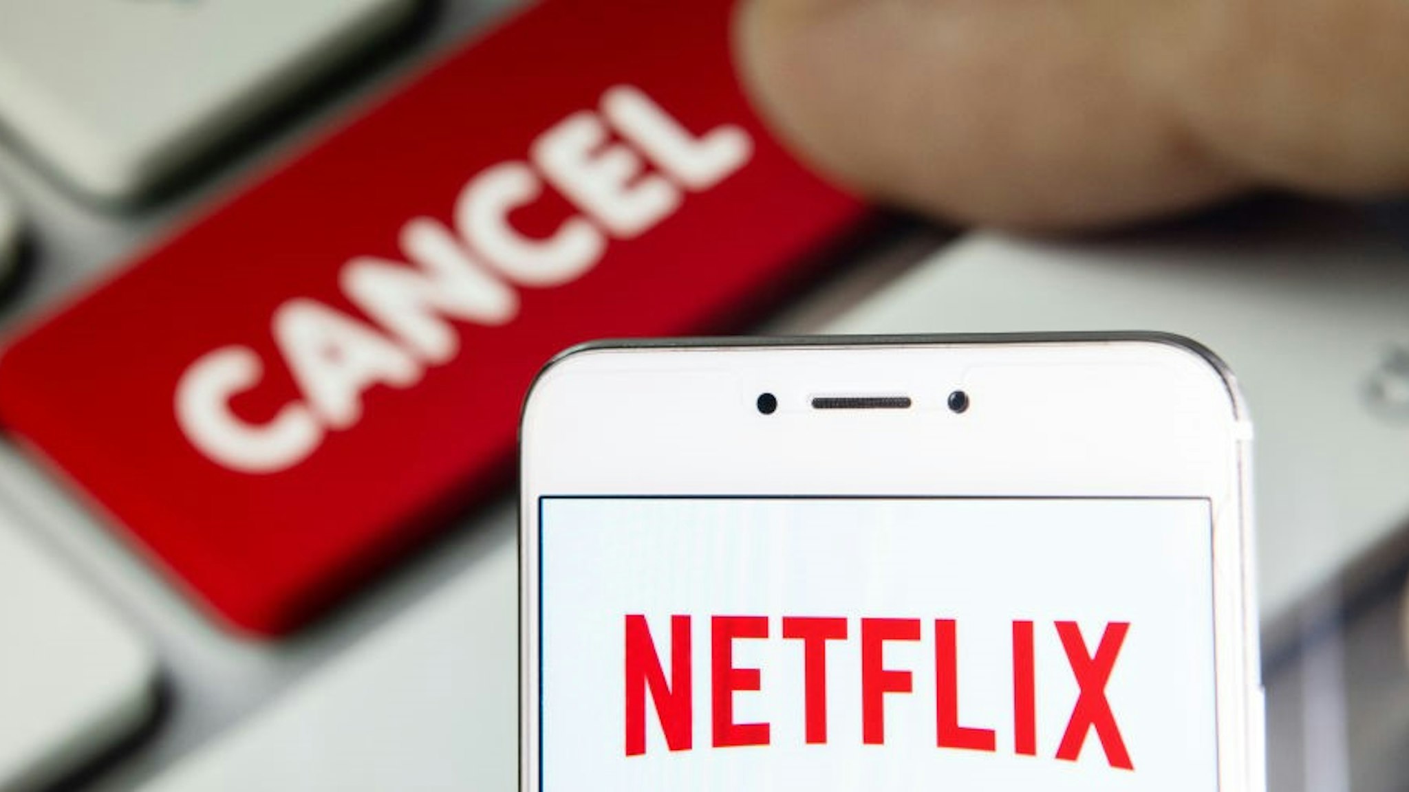 In this photo illustration a American global on-demand Internet streaming media provider Netflix logo is seen on an Android mobile device with a computer key which says cancel.