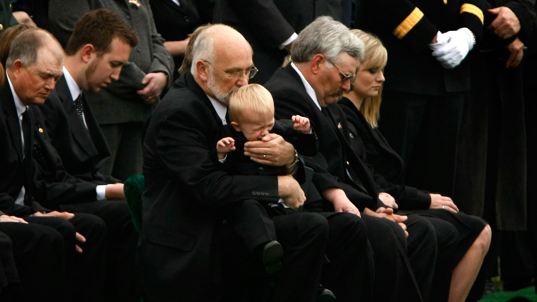 ARLINGTON, WA - APRIL 08: Peter Hake comforts his 18-month old grandson Gage during the burial service for his son, Army SSG Christopher M. Hake, at Arlington National Cemetery April 8, 2008 in Arlington, Virginia.