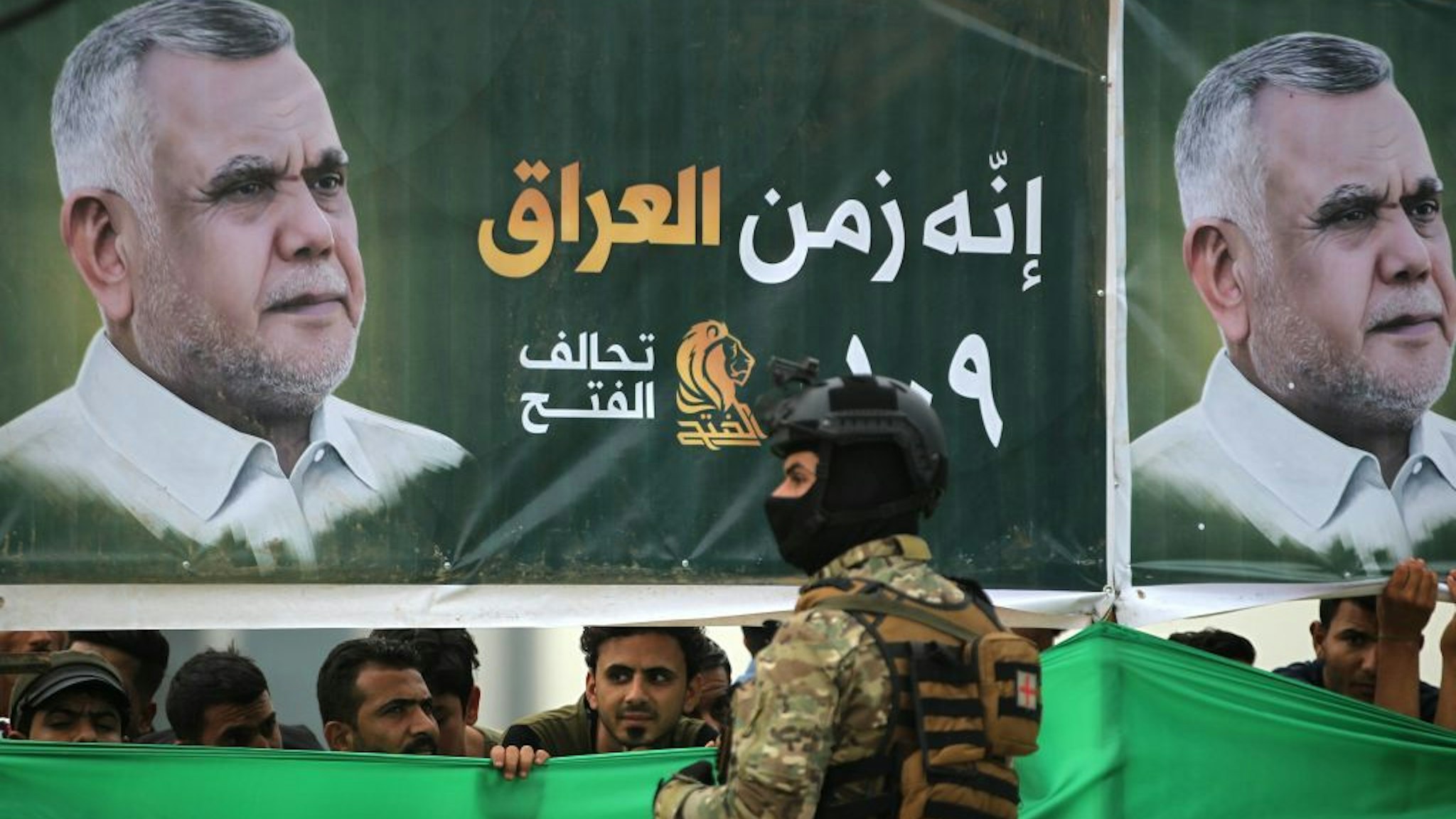 Iraqi supporters of the Fateh Alliance, a coalition of Iranian-supported militia groups, listen to a speech by Hadi Amiri (portrait), head of the Iranian-backed Badr Organization and leader of the Fateh Alliance, during a campaign rally in Baghdad on May 7, 2018, ahead of Iraq's parliamentary elections to be held on May 12. (Photo by AHMAD AL-RUBAYE / AFP) (Photo credit should read AHMAD AL-RUBAYE/AFP via Getty Images)