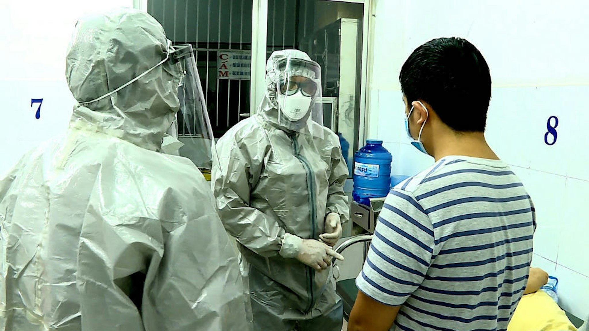 Medical personnel wearing protectice suits interact with two patients (R on bed and standing) tested positive to the coronavirus in an isolation room at Cho Ray hospital in Ho Chi Minh City on January 23, 2020. - Two Chinese nationals in Vietnam have tested positive for the SARS-like coronavirus and are being treated in hospital, officials said on January 23. (Photo by STR / Vietnam News Agency / AFP)