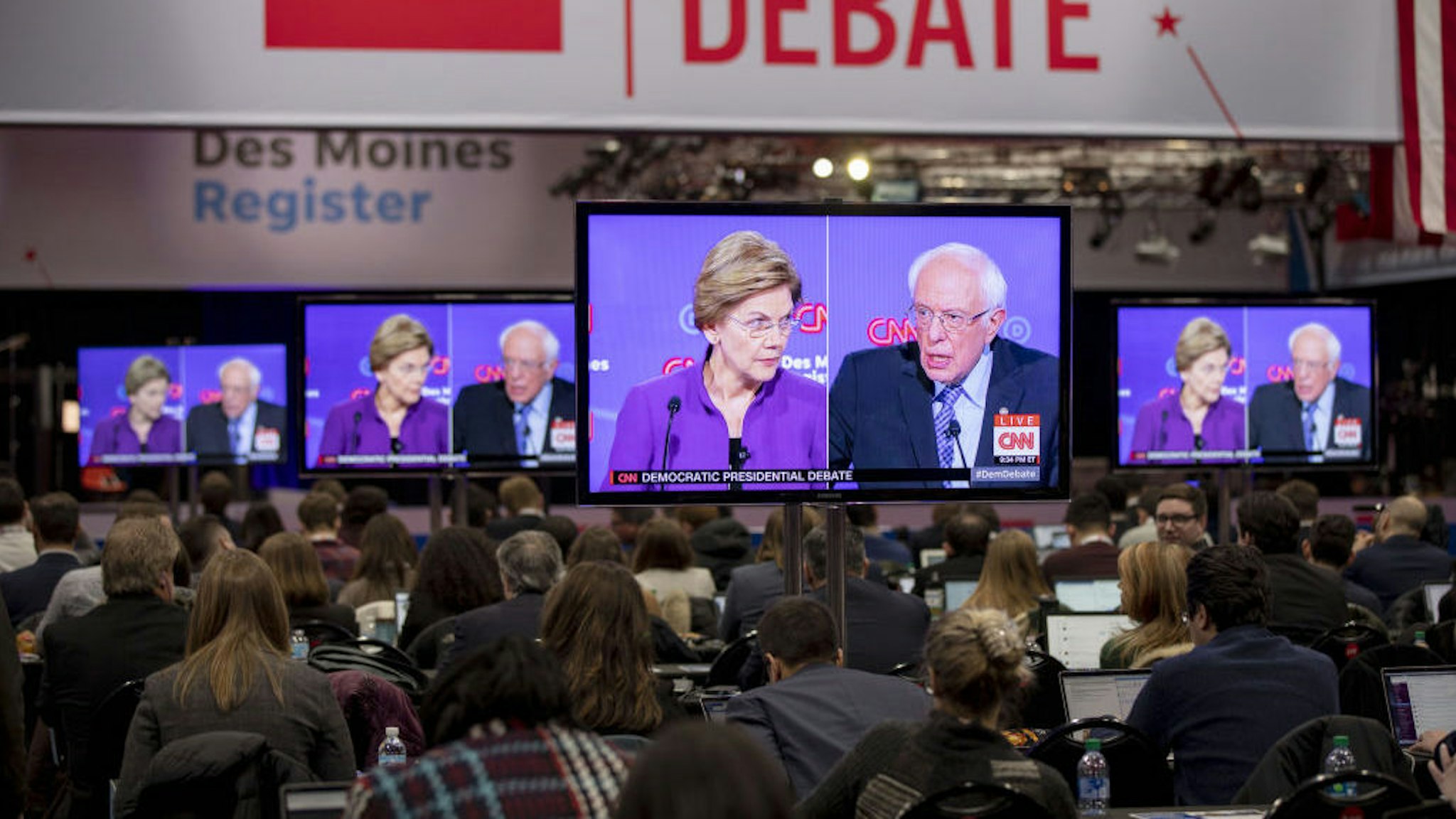 2020 Democratic presidential candidates Senator Elizabeth Warren, a Democrat from Massachusetts, left, and Senator Bernie Sanders, an independent from Vermont, are seen on television screens in the media center during the Democratic presidential debate in Des Moines, Iowa, U.S., on Tuesday, Jan. 14, 2020. The longstanding nonaggression pact between Elizabeth Warren and Bernie Sanders will be under strain at the seventh Democratic presidential debate Tuesday night after recent reports that Sanders has questioned whether a woman could get elected president. Photographer: Daniel Acker/Bloomberg