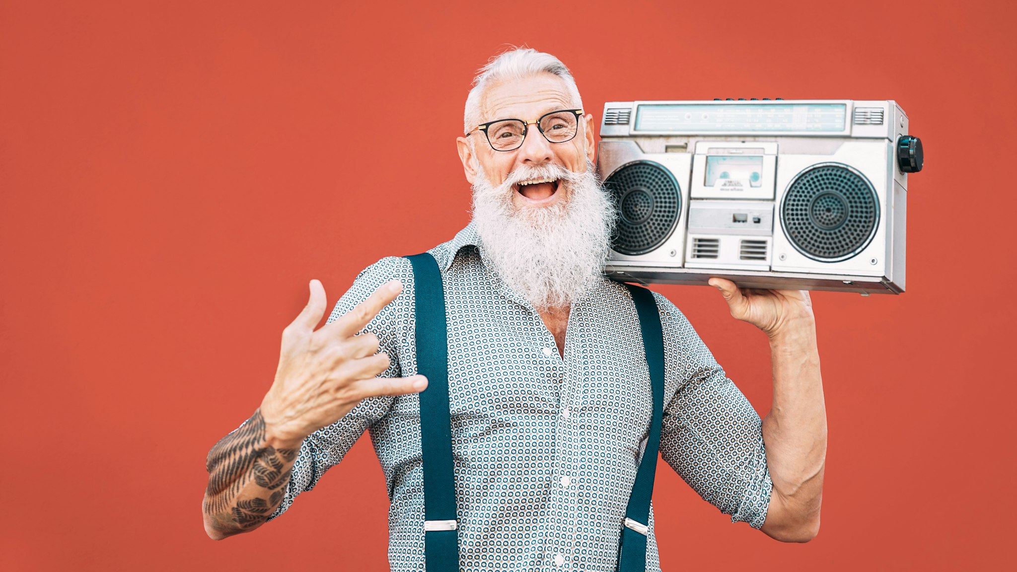 Hipster Senior Man Listening Music On Radio Against Red Background - stock photo