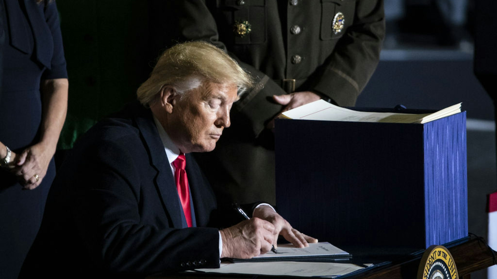 U.S. President Donald Trump signs the National Defense Authorization Act for Fiscal Year 2020 during a ceremony at Joint Base Andrews, Maryland, U.S., on Friday, Dec. 20, 2019.