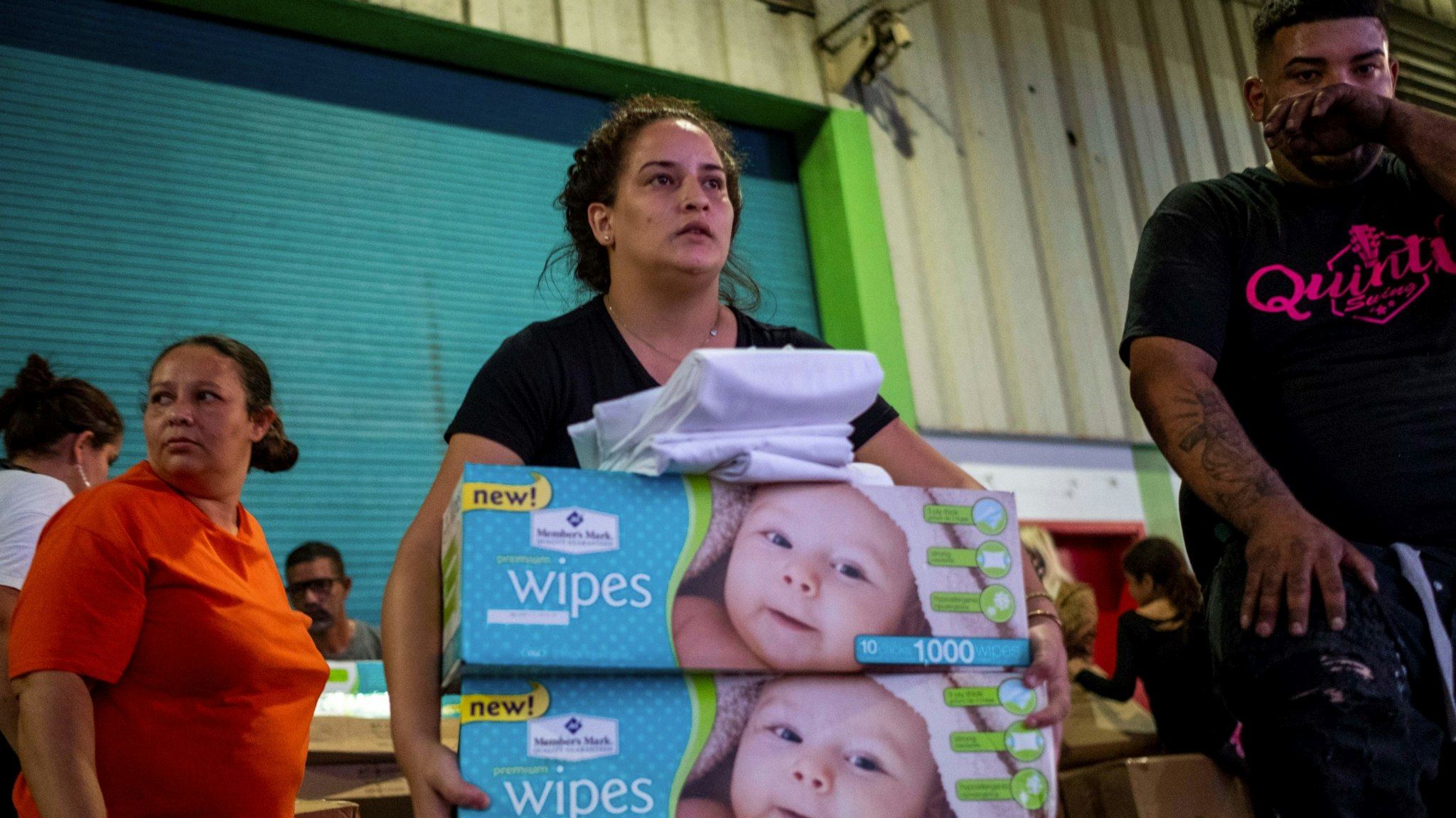 A woman carries boxes of baby wipes she removed from a warehouse filled with supplies, including thousands of cases of water, believed to have been from when Hurricane Maria struck the island in 2017 in Ponce, Puerto Rico on January 18, 2020, after a powerful earthquake hit the island. - President Donald Trump on January 16 freed up emergency aid for Puerto Rico's recovery from a January 7 earthquake that caused widespread disruption and damage on the island. Trump's declaration of a major disaster in Puerto Rico makes federal funding available for repairs, temporary housing and low-cost loans "to help individuals and business owners recover from the effects of the disaster," the White House said. (Photo by Ricardo ARDUENGO / AFP) (Photo by RICARDO ARDUENGO/AFP via Getty Images)