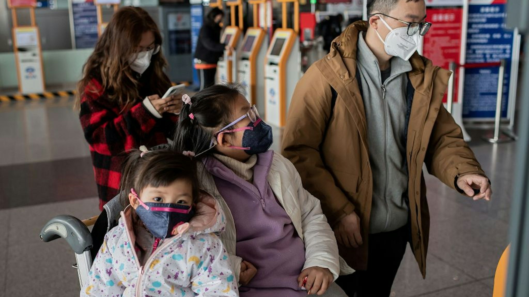 People travelling for the Lunar New Year wear protective masks as they head to the departure area at the Beijing Capital International Airport in Beijing on January 22, 2020.