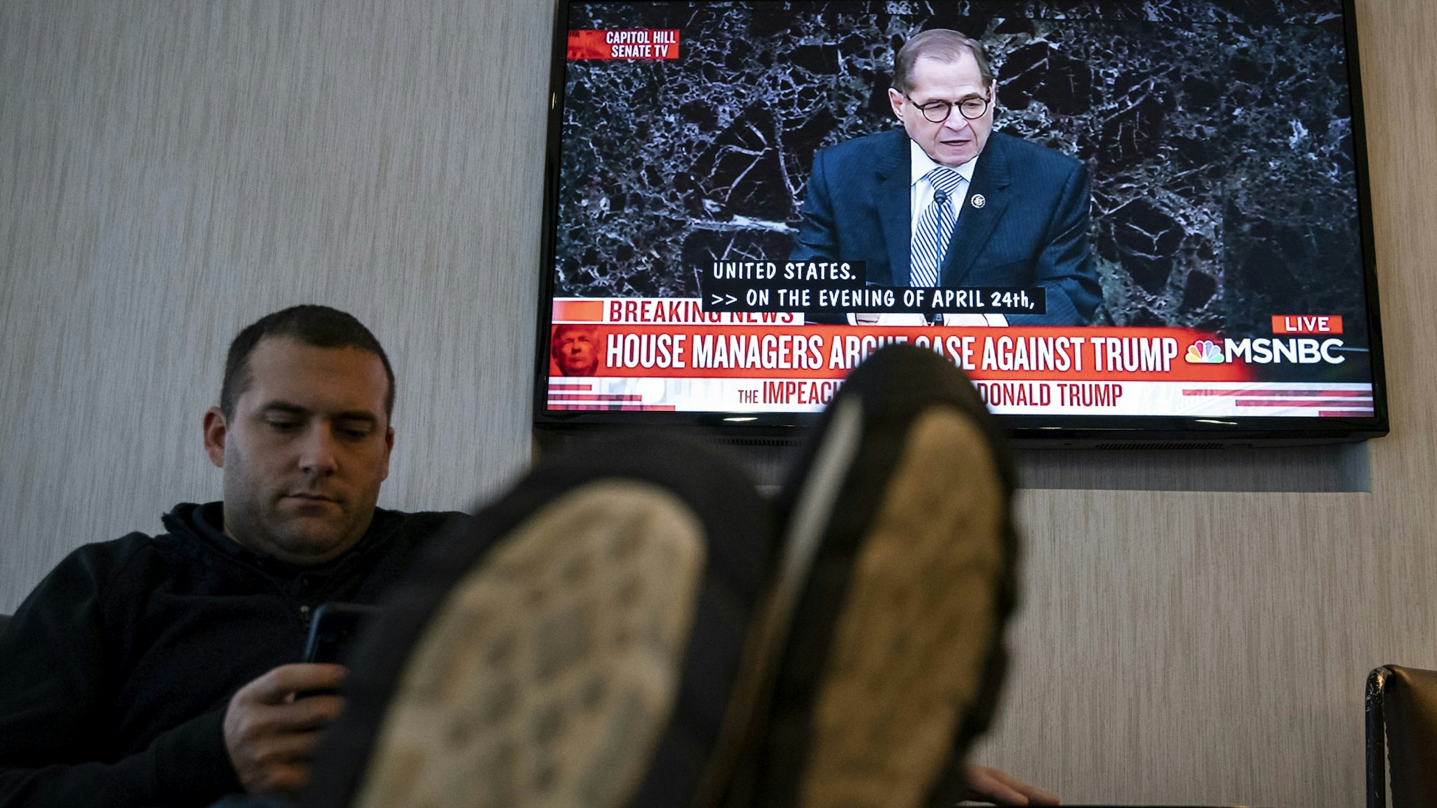 DES MOINES, IA - JANUARY 22: A man uses his cell phone as a television screen shows House impeachment manager Rep. Jerry Nadler (D-NY) during the Senate impeachment trial of U.S. President Donald Trump, on January 22, 2020 at a hotel in Des Moines, Iowa. The senate impeachment trial of President Trump, which requires all senators to be present at Capitol Hill, has made it difficult for a number of democratic candidates to campaign in Iowa with less than two week until the caucus. (Photo by Al Drago/Getty Images)