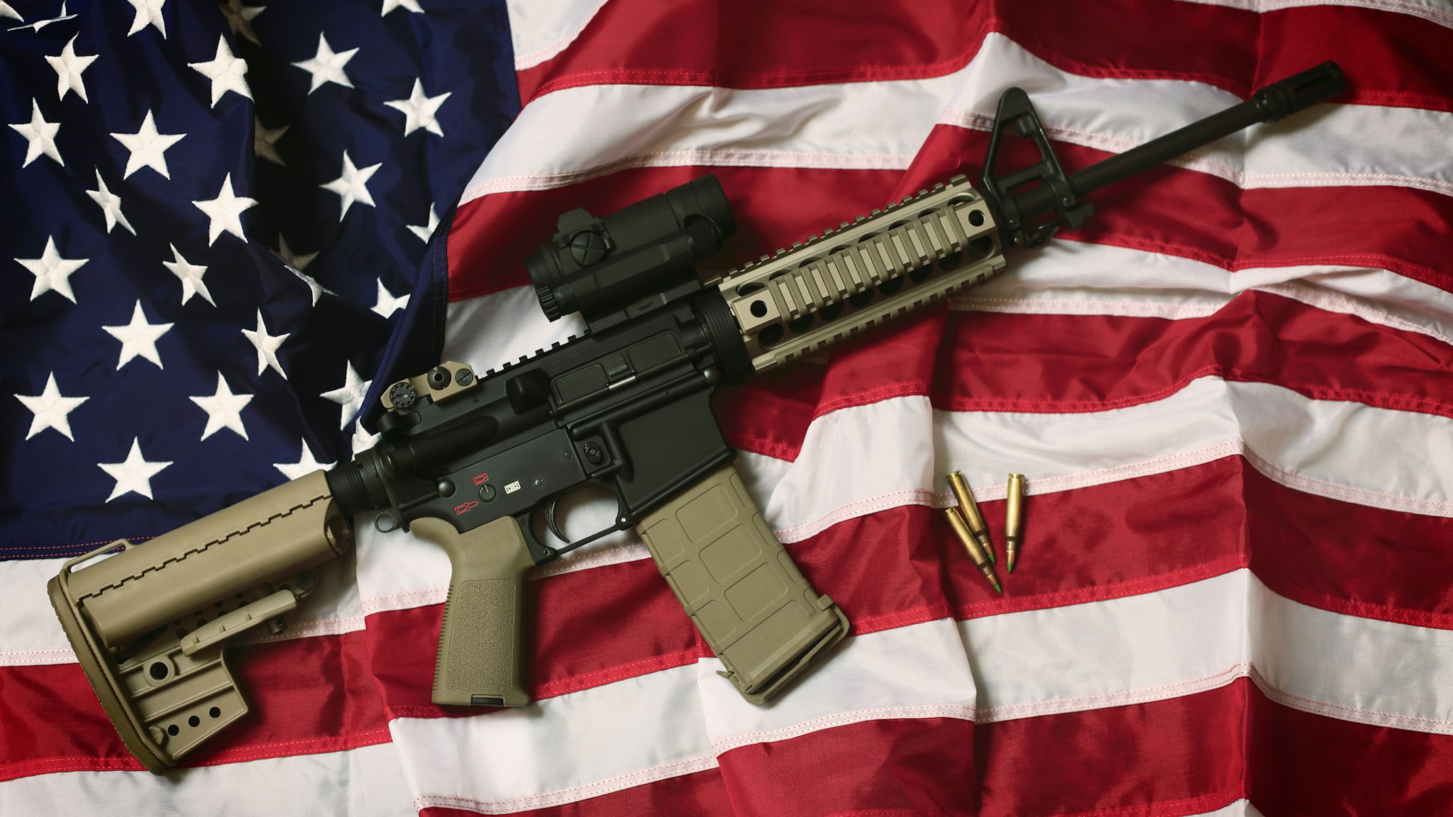 An AR-15 rifle with bullets on an American flag, a symbol of the right of patriotic Americans to bear arms, guaranteed by the Second Amendment.