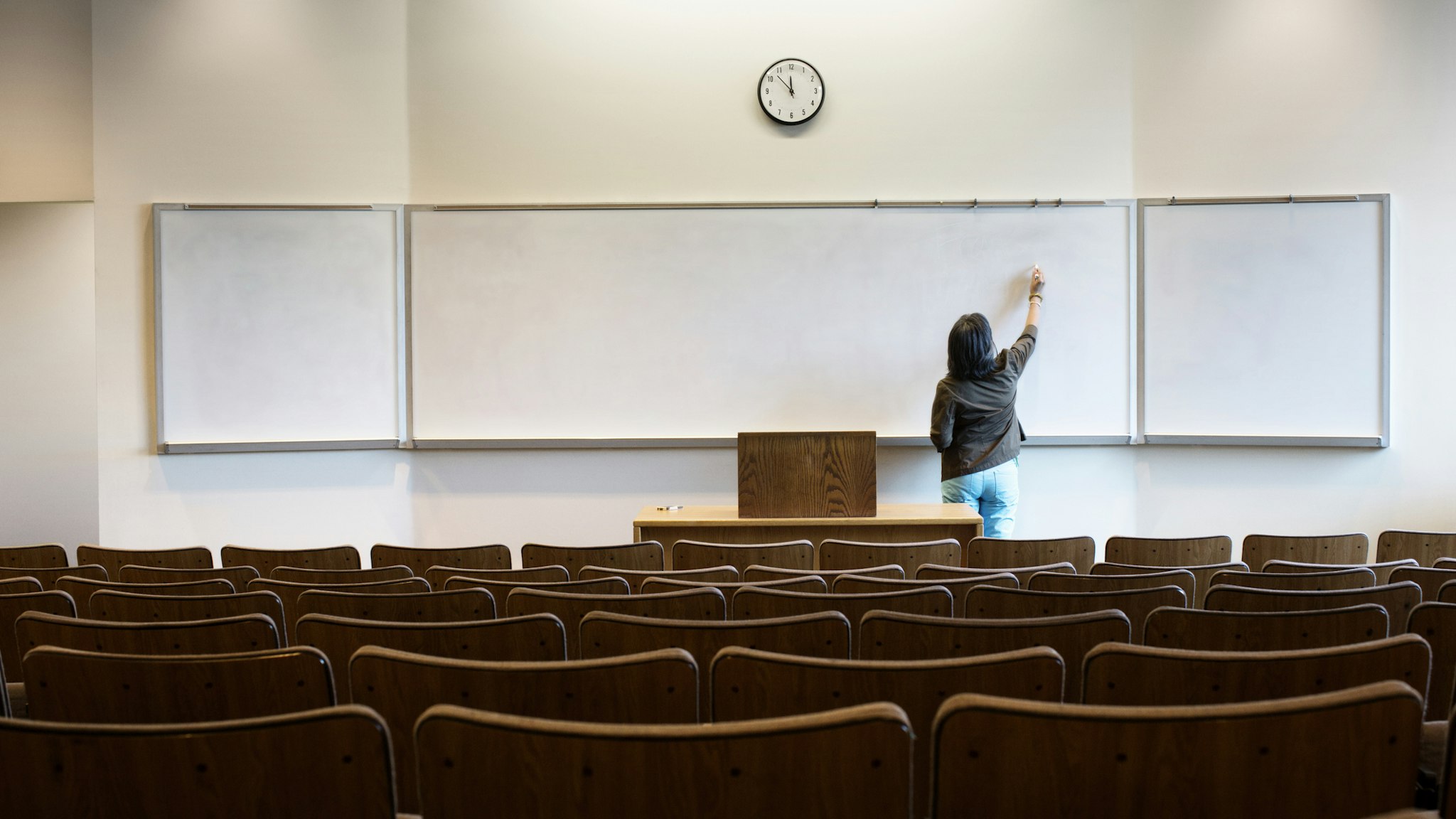 Filipino professor writing on whiteboard in empty lecture hall - stock photo