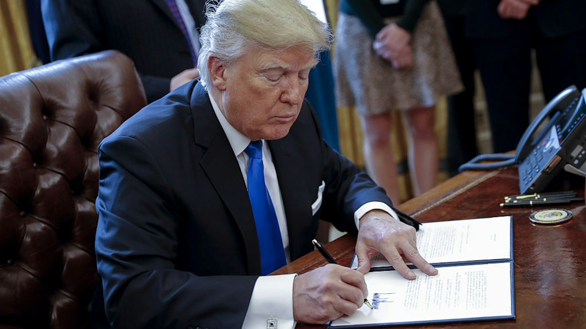 US President Donald Trump signs one of five executive orders related to the oil pipeline industry in the Oval Office of the White House in Washington, D.C., U.S., Tuesday, Jan. 24, 2017.