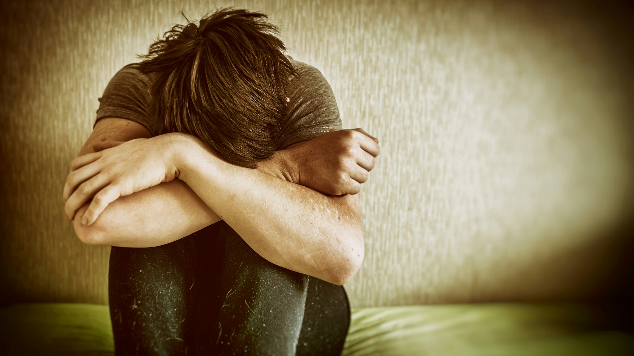 Sad Young Man Sitting On Bed At Home - stock photo