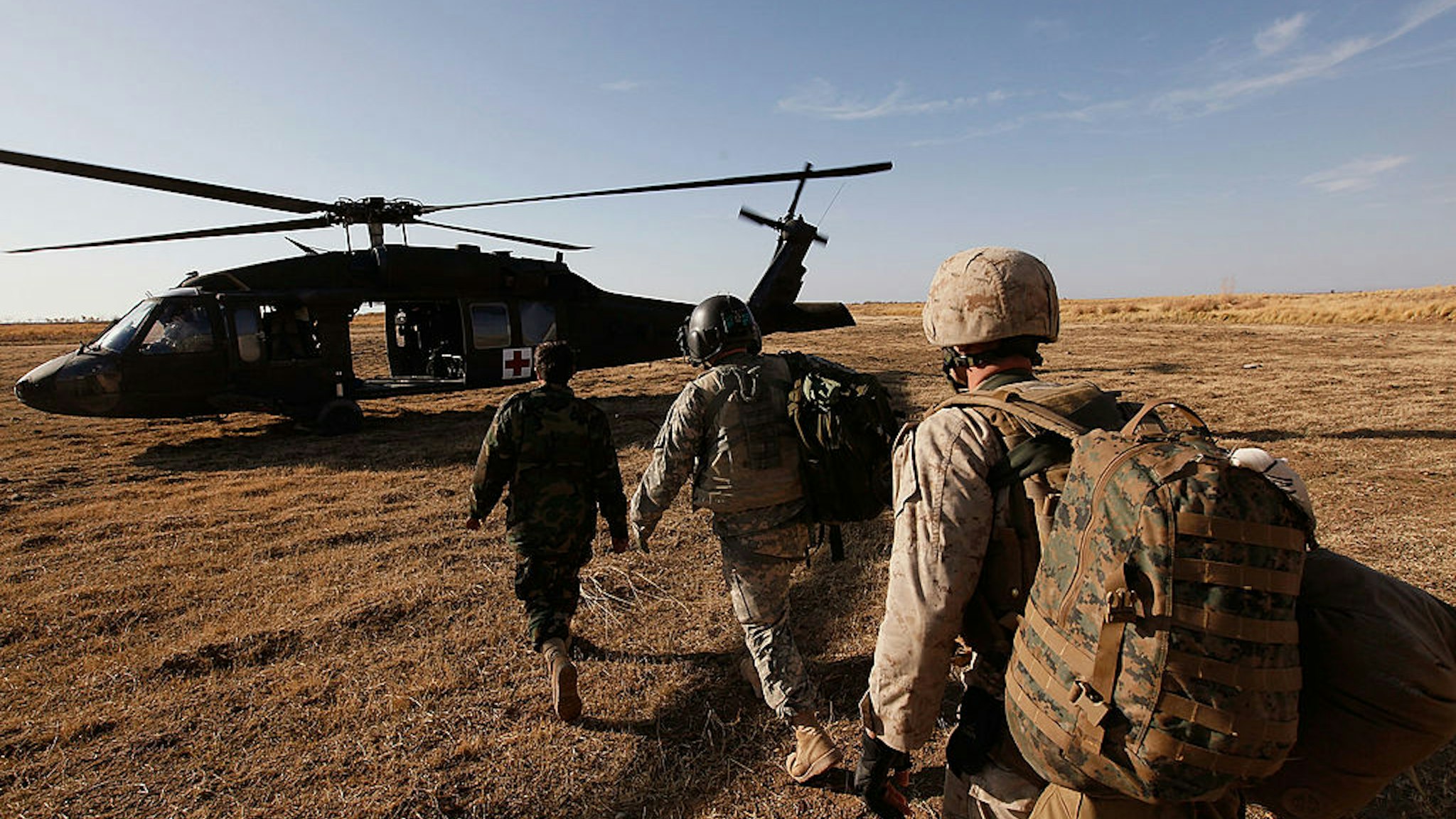 Flight medic Sgt. Aaron Burrows (C) of Amarillo, TX with C Company Dustoff 3rd Battalion of the 82nd Combat Aviation Brigade 82nd Airborne Division leads a U.S. Marine (R) and a soldier with the Afghan National Army to a MEDEVAC helicopter December 20, 2009 near Delhi, Afghanistan.