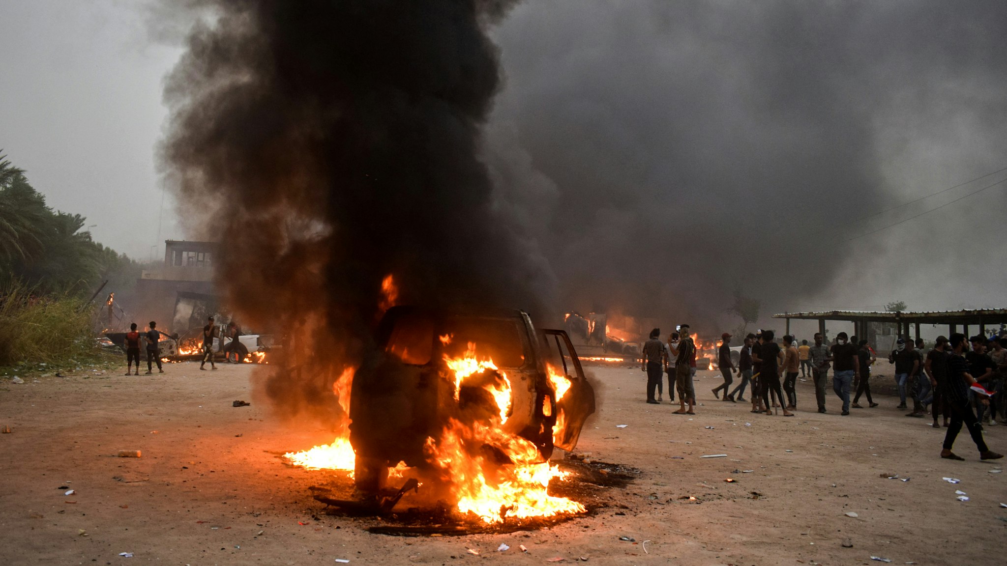 This picture taken on October 25, 2019 shows a burning car at the scene of anti-government demonstrations outside the burning local government headquarters in Nasiriyah, the capital of Iraq's southern province of Dhi Qar.