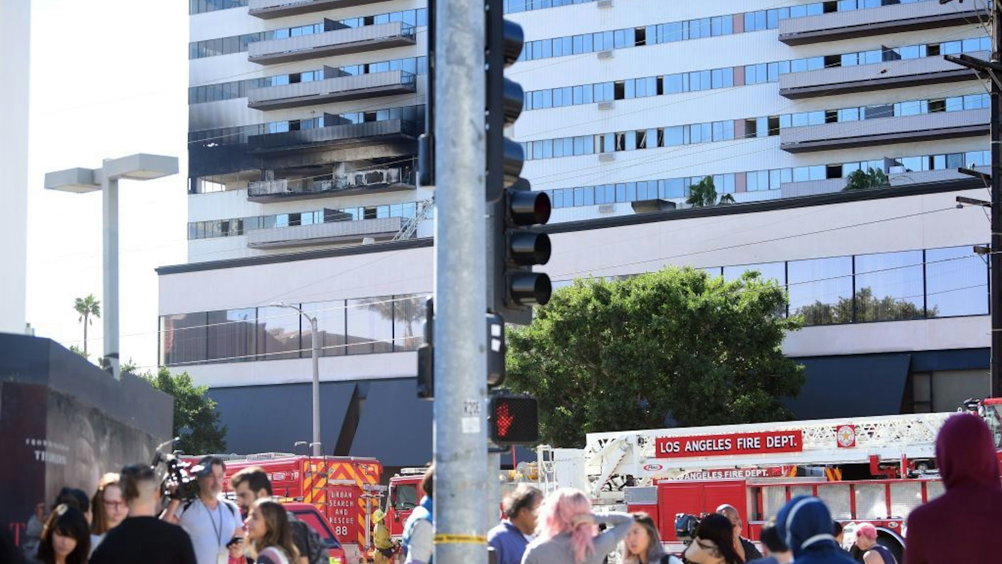 People stand outside the building after a fire on January 29, 2020 in Los Angeles, California. - A fire suspected to have been started deliberately January 29, 2020 in a high-rise residential block in Los Angeles injured eight people, including a baby, and prompted a massive response by firefighters.Earlier reports had said several people had jumped from the 25-story Barrington Plaza in the west of the city but authorities later clarified that was not the case."No one jumped, there are no fatalities," deputy fire chief Armando Hogan told reporters. "Two people contemplated jumping but we told them to stay where they were." (Photo by FREDERIC J. BROWN / AFP)