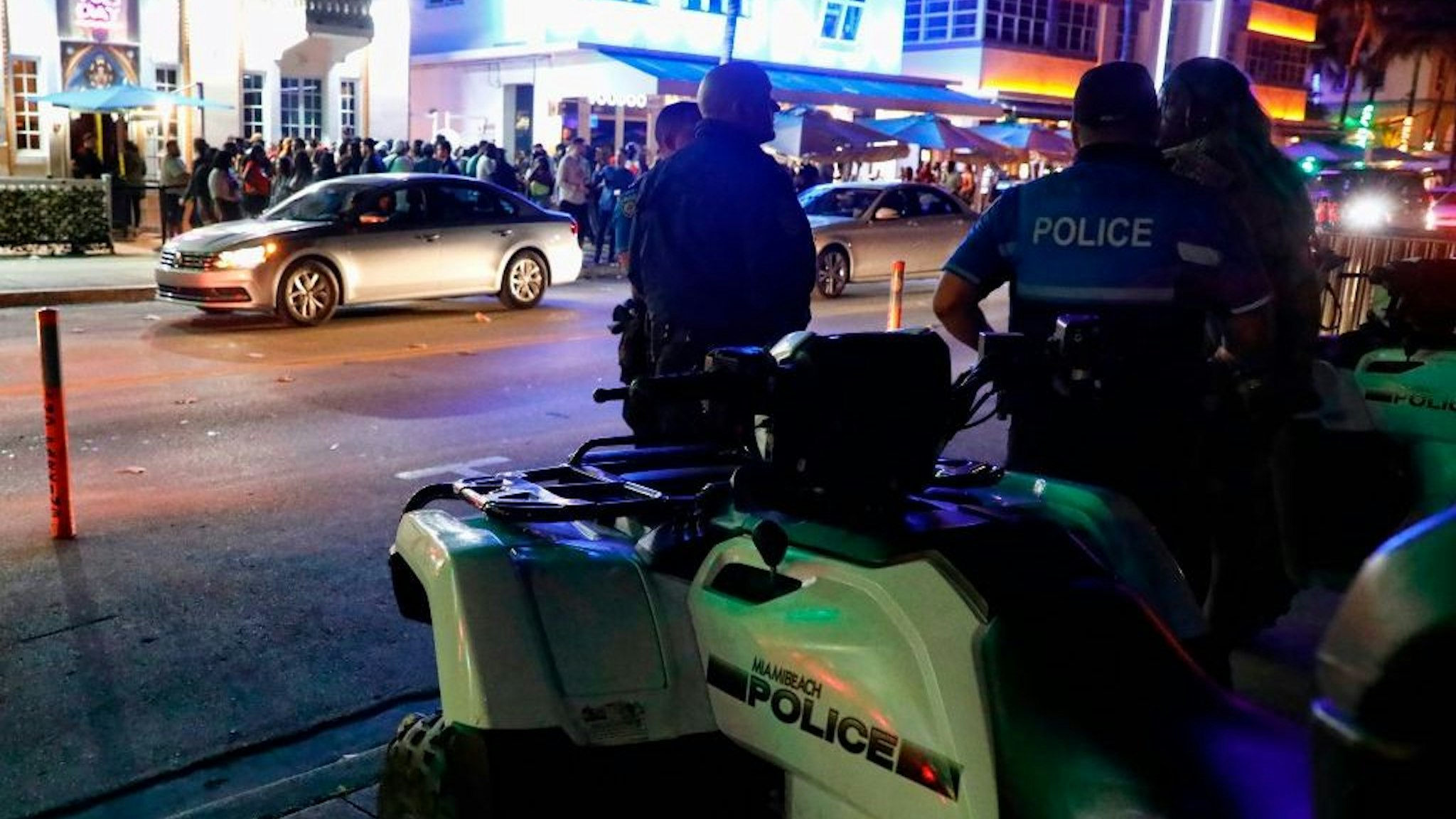 Miami Beach police officers stand across the street from the night clubs and hotels on Ocean Drive in South Beach, Florida on March 22, 2019. - The excesses of students celebrating Spring Break have reached a point that is forcing Miami Beach officials to deploy anti-riot police to quell the party. Police are also promising to stop turning a blind eye to drinking alcohol on the beach and the smoking of marijuana. (Photo by RHONA WISE / AFP)
