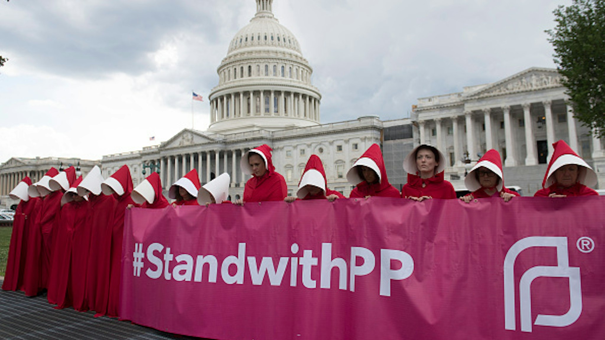 Supporters of Planned Parenthood dressed as characters from "The Handmaid's Tale," hold a rally as they protest the US Senate Republicans' healthcare bill outside the US Capitol in Washington, DC, June 27, 2017. / AFP PHOTO / SAUL LOEB