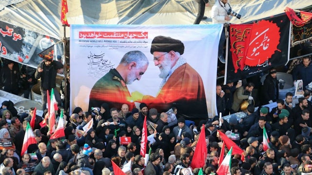 Iranian mourners carry a picture of Iran's Supreme Leader Ayatollah Ali Khamenei (R) granting the Order of Zolfaghar, the highest military honour of Iran, to General Qasem Soleimani, during the latter's funeral procession in the capital Tehran on January 6, 2020. - Downtown Tehran was brought to a standstill as mourners flooded the Iranian capital to pay an emotional homage to Soleimani, the "heroic" general who spearheaded Iran's Middle East operations as commander of the Revolutionary Guards' Quds Force and was killed in a US drone strike on January 3 near Baghdad airport along with Iraqi paramilitary chief Abu Mahdi al-Muhandis and others. (Photo by ATTA KENARE / AFP)