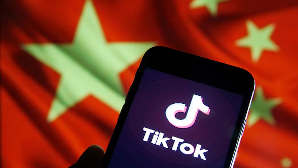 TikTok : Illustration PARIS, FRANCE - DECEMBER 26: In this photo illustration the logo of Chinese media app for creating and sharing short videos, TikTok, also known as Douyin is displayed on the screen of a smartphone in front of a Chinese flag on December 26, 2019 in Paris, France. The social media app TikTok developed by Chinese company ByteDance continues its meteoric rise and exceeded the milestone of 1.5 billion downloads. Tik Tok now surpasses Facebook and Instagram.
