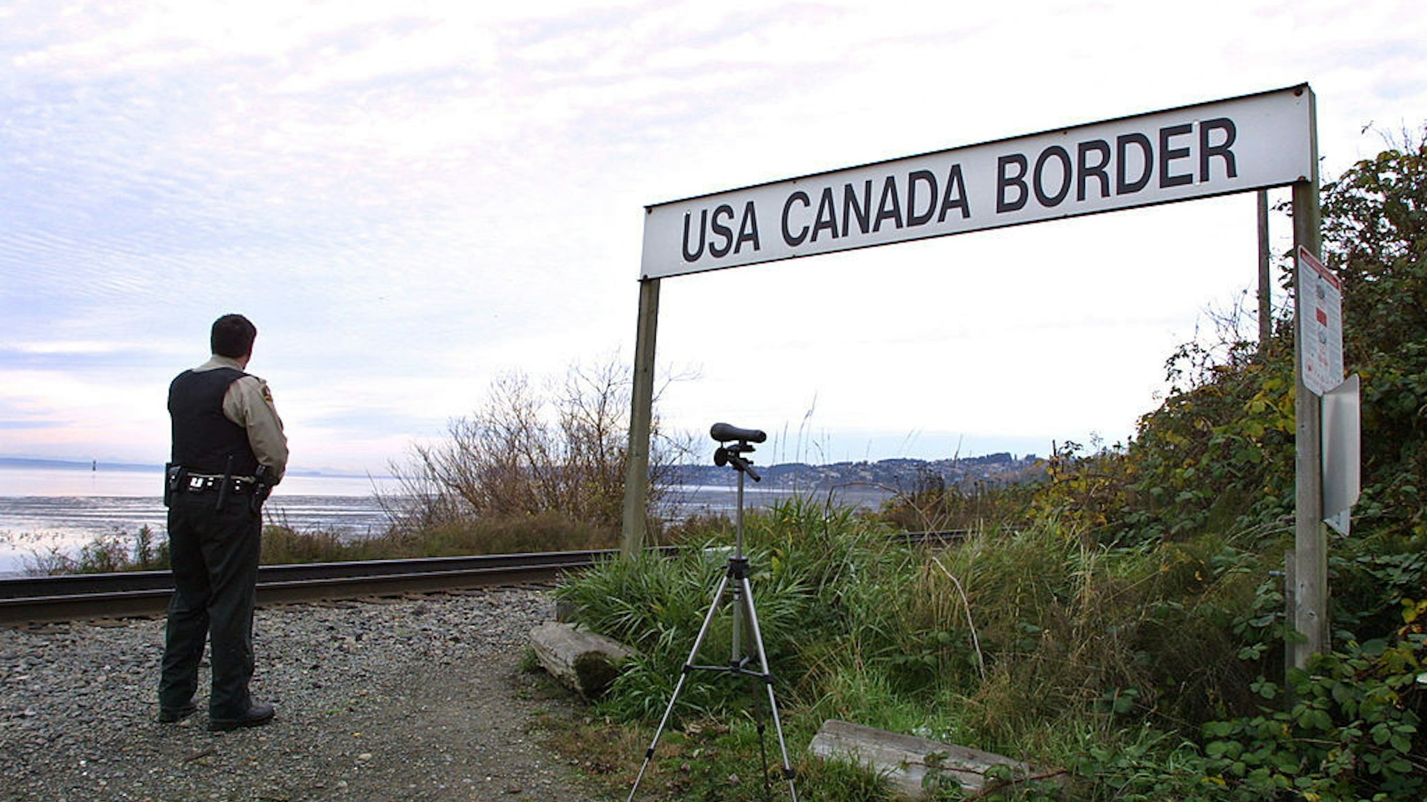 A Canadian Customs and Fisheries officer watches over the U.S.-Canada border between Blaine, Washington and White Rock, British Columbia November 8, 2001 in White Rock, BC. The Peace Arch border crossing is one of the busiest crossings in North America. (Photo by Jeff Vinnick/Getty Images)