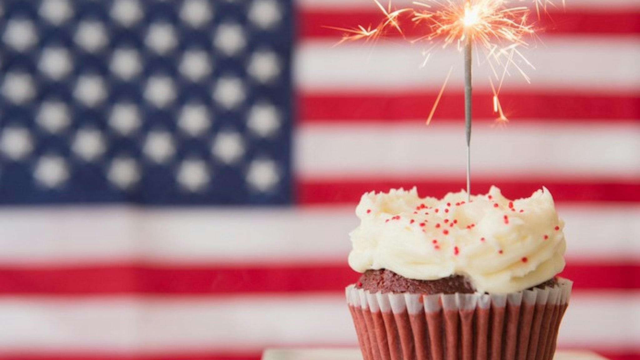 A cupcake stands in front of an American flag