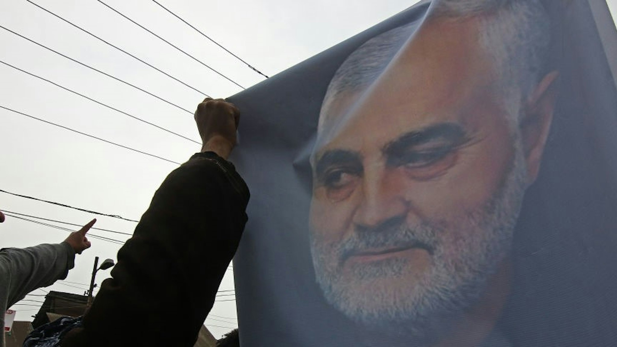 A Kashmiri Shiite muslim holds a picture of Iranian military General Qassem Soleimani as he marches during an anti-America protest in central Kashmir on January 03, 2020.The agitated protesters were chanting anti-America slogans and staged a protest against the killing of Soleimani by a US air strike in Baghdad.
