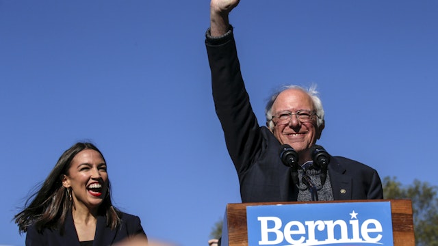 NEW YORK, NY - OCTOBER 19: Democratic presidential candidate, Sen. Bernie Sanders (I-VT) waves with Rep. Alexandria Ocasio-Cortez (D-NY) as she endorses him during his speech at a campaign rally in Queensbridge Park on October 19, 2019 in the Queens borough of New York City. This is Sanders' first rally since he paused his campaign for the nomination due to health problems.