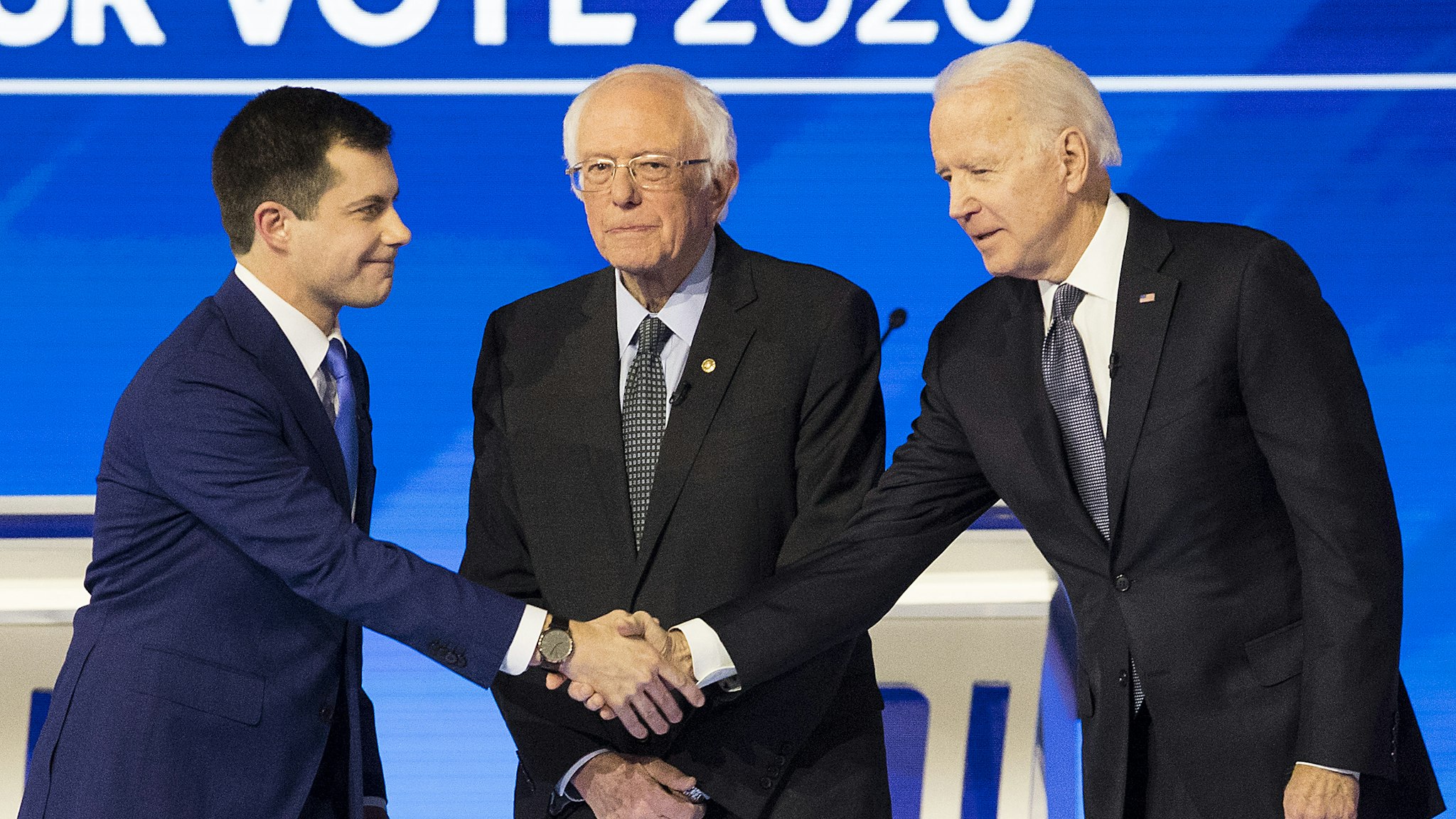 Pete Buttigieg, former mayor of South Bend and 2020 presidential candidate, left, shakes hands with Former Vice President Joe Biden, as Senator Bernie Sanders, an Independent from Vermont, stands on stage ahead of the Democratic presidential debate at Saint Anselm College in Manchester, New Hampshire, U.S., on Friday, Feb. 7, 2020. The New Hampshire debates often mark a turning point in a presidential campaign, as the field of candidates is winnowed and voters begin to pay closer attention.