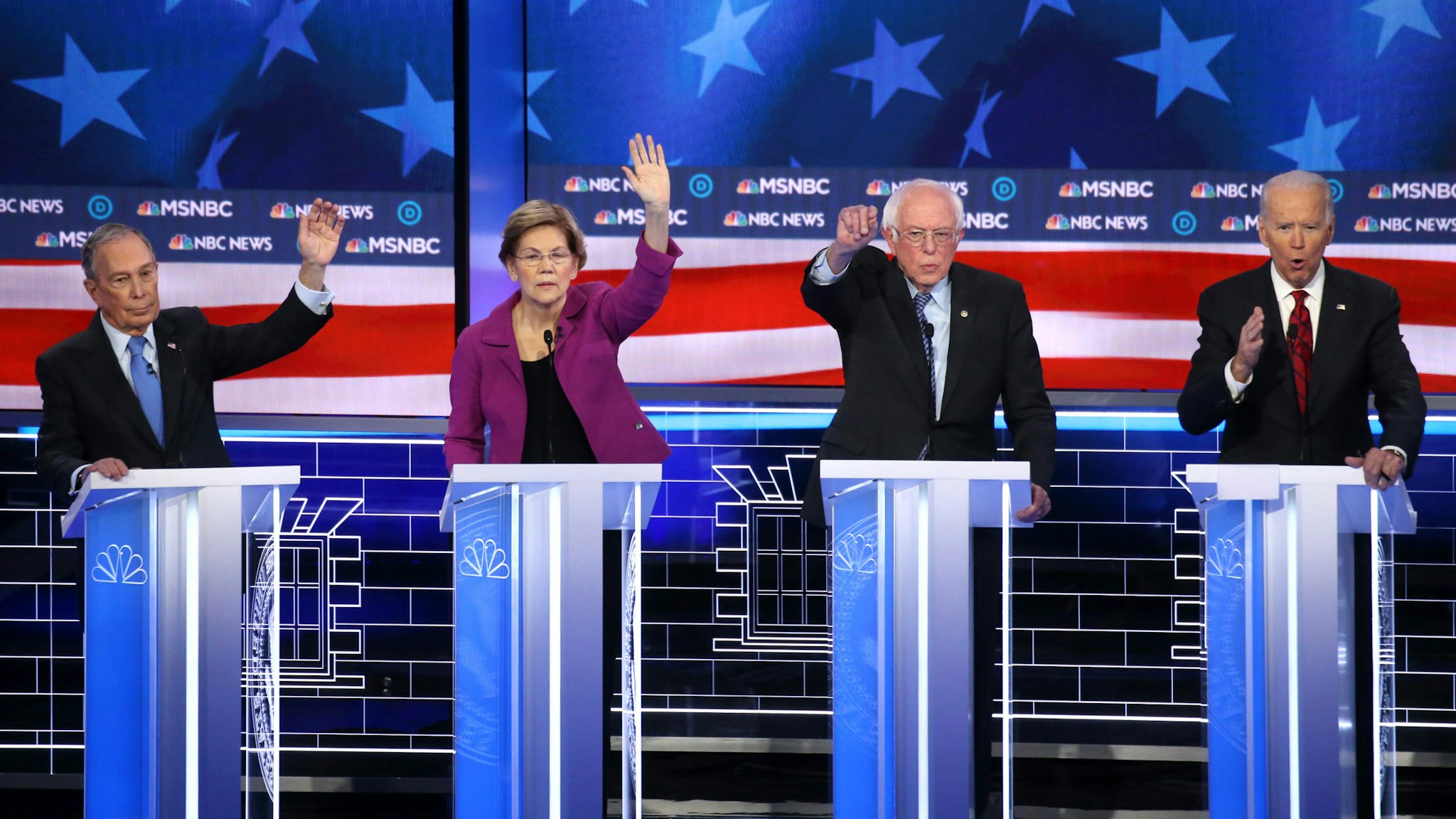 LAS VEGAS, NEVADA - FEBRUARY 19: Democratic presidential candidates (L-R) former New York City mayor Mike Bloomberg, Sen. Elizabeth Warren (D-MA) and Sen. Bernie Sanders (I-VT) raise their hands as former Vice President Joe Biden (R) speaks during the Democratic presidential primary debate at Paris Las Vegas on February 19, 2020 in Las Vegas, Nevada. Six candidates qualified for the third Democratic presidential primary debate of 2020, which comes just days before the Nevada caucuses on February 22.