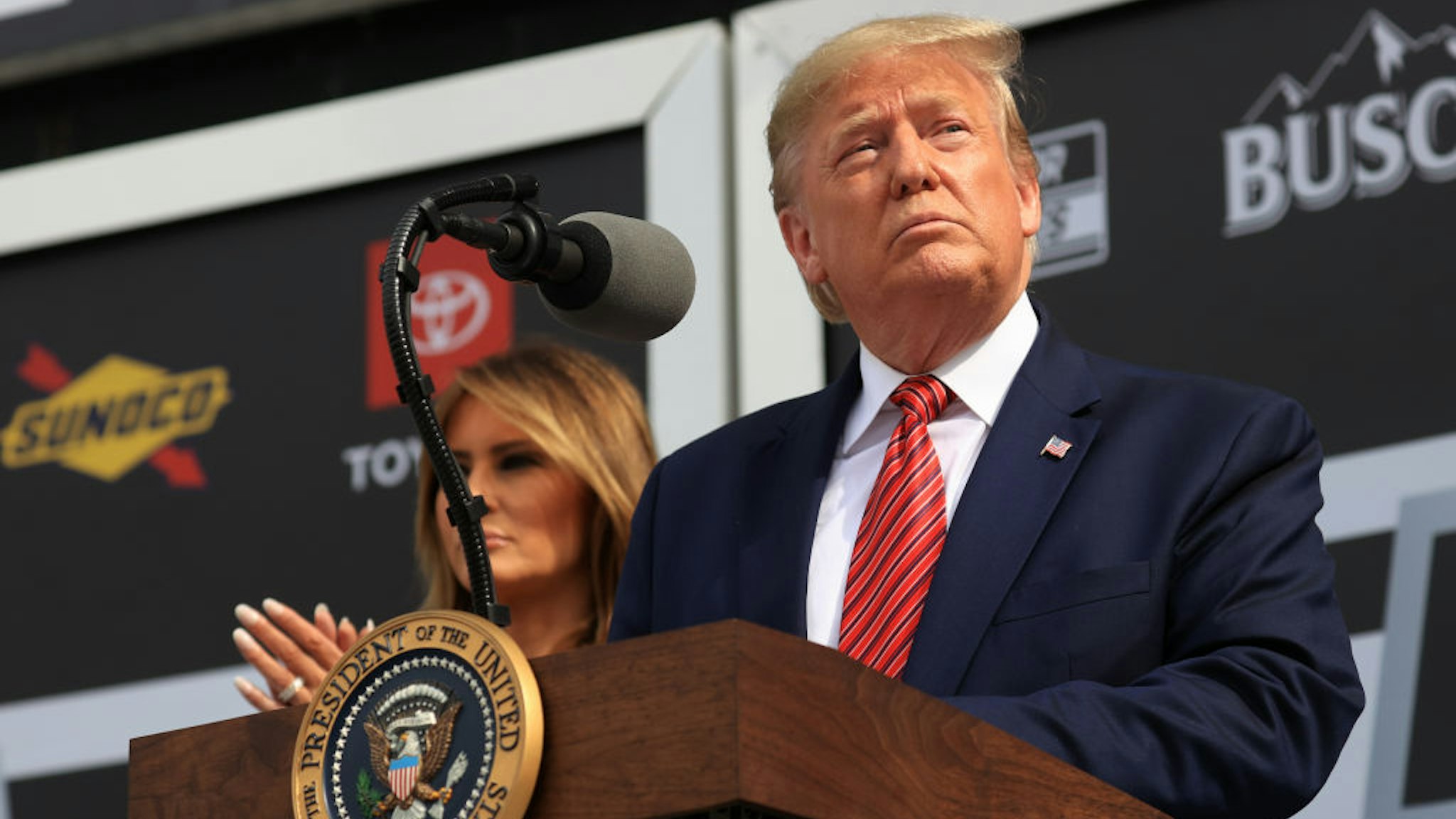 U.S. President Donald Trump speaks as First Lady Melania Trump looks on from Victory Lane prior to the NASCAR Cup Series 62nd Annual Daytona 500 at Daytona International Speedway on February 16, 2020 in Daytona Beach, Florida. (Photo by Chris Graythen/Getty Images)