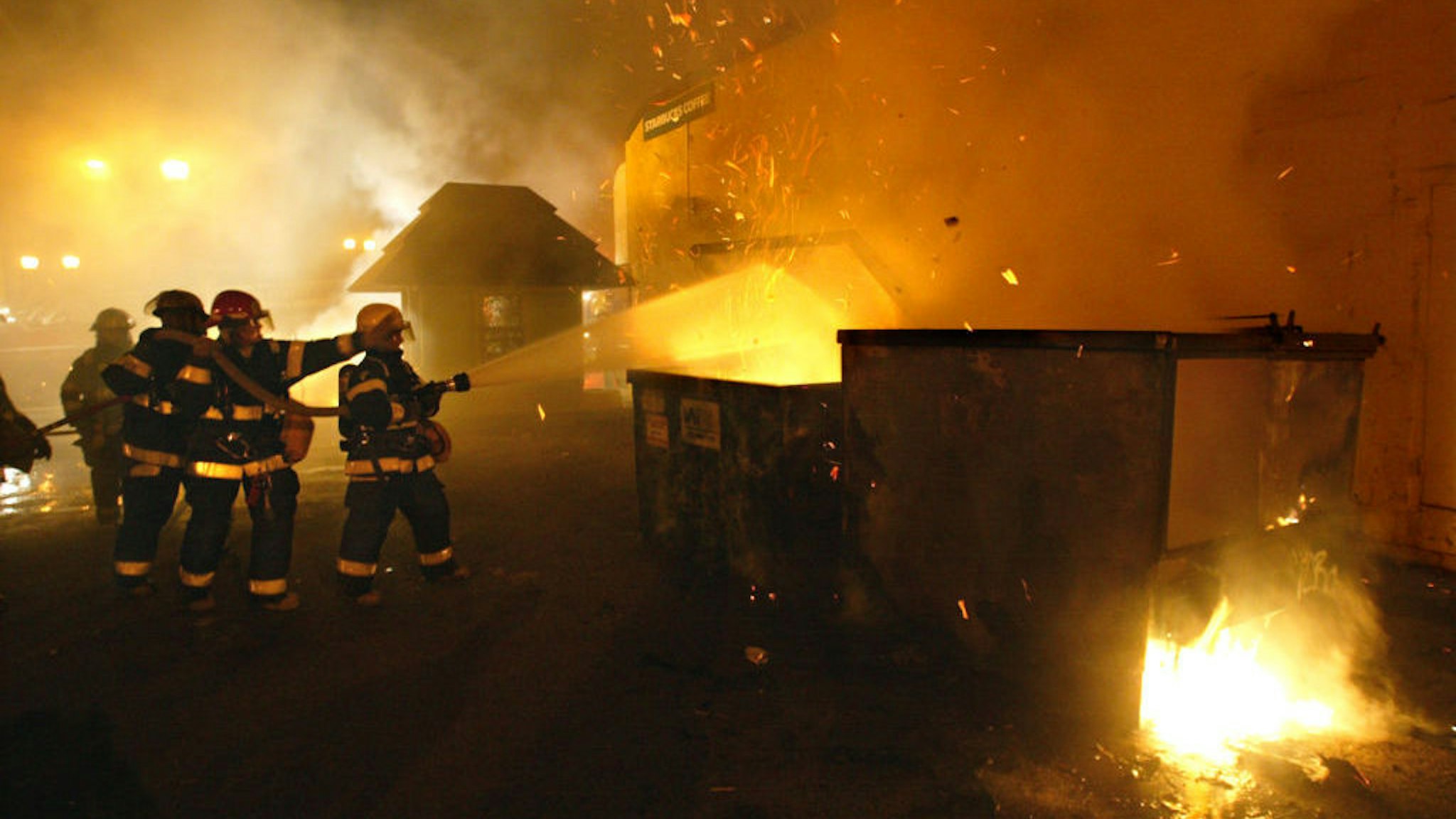 Minneapolis firemen put out a fire in a garbage dumpster in a parking lot next to Starbucks Coffee on the University of Minnesota campus. The fires were set by students rioting after the Gopher hockey team won the national title.