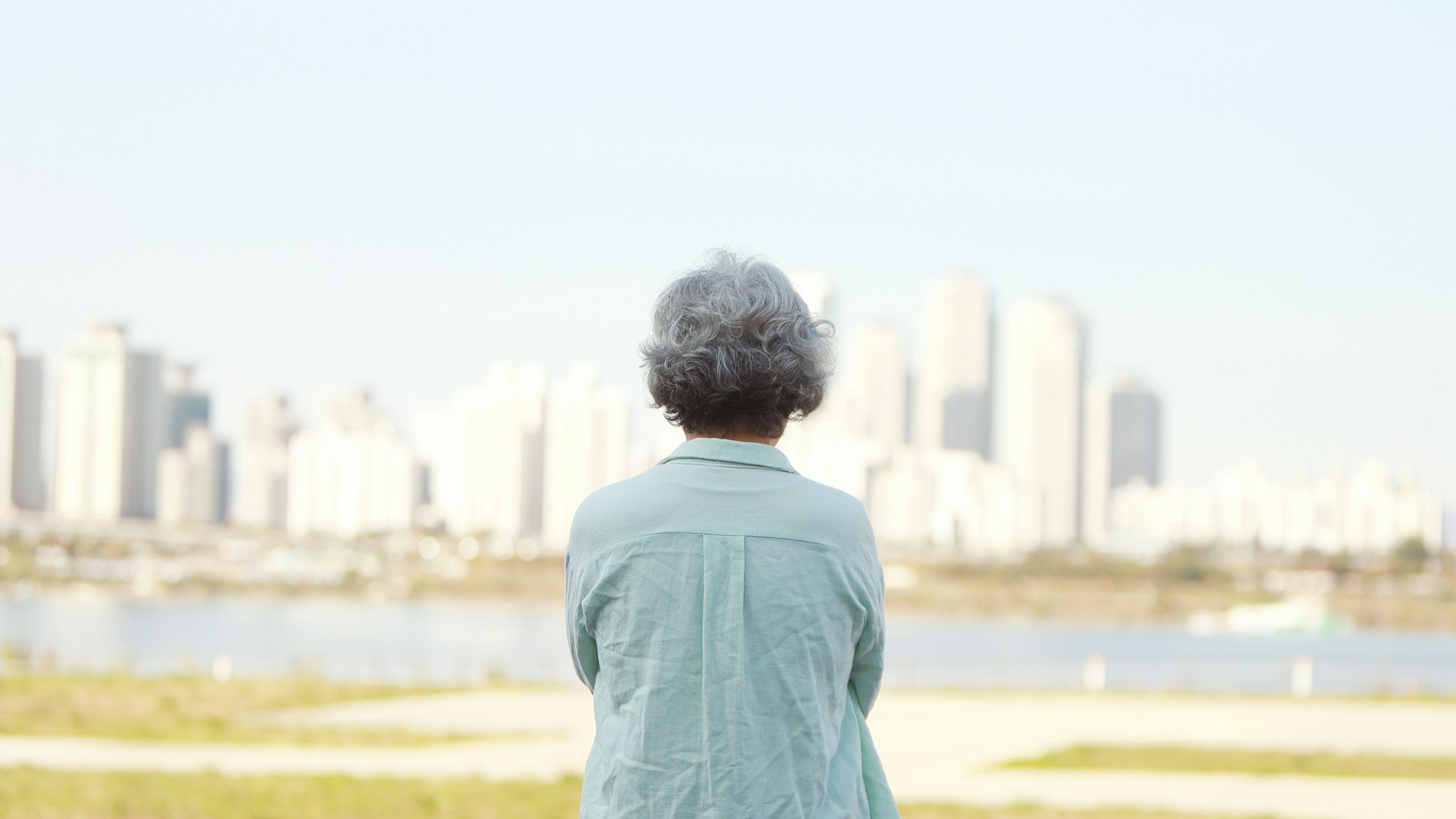 Rear view of senior woman standing by river bank - stock photo