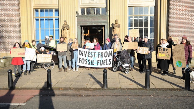 Protesters hold placards and a banner that says divest from fossil fuels during the demonstration.