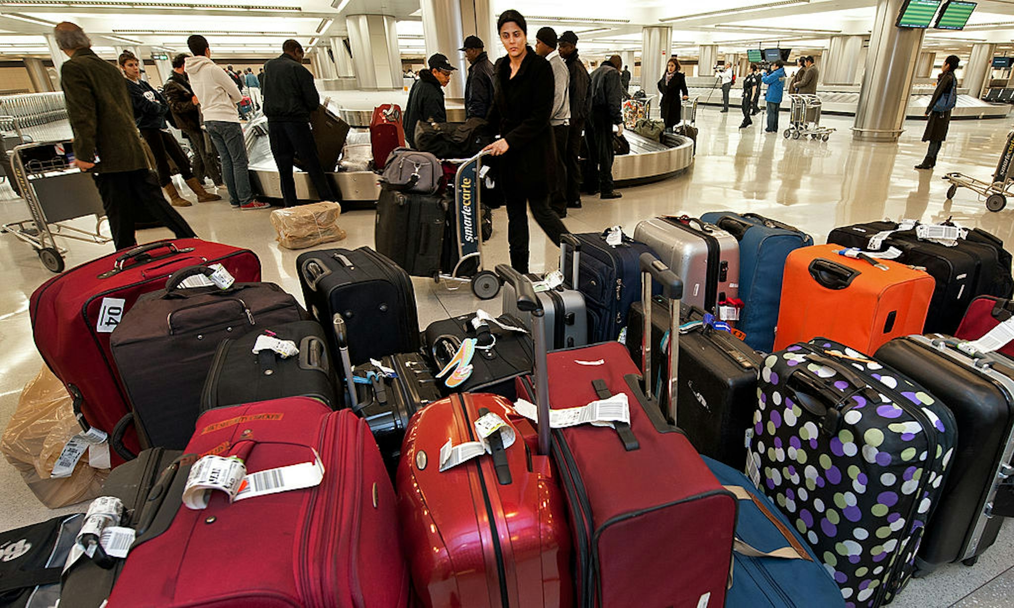 A woman pushes her luggage cart past unclaimed bags inside the US Customs and Border Protection inspection area at Dulles International Airport (IAD), December 21, 2011 in Sterling, Virgina, near Washington, DC.