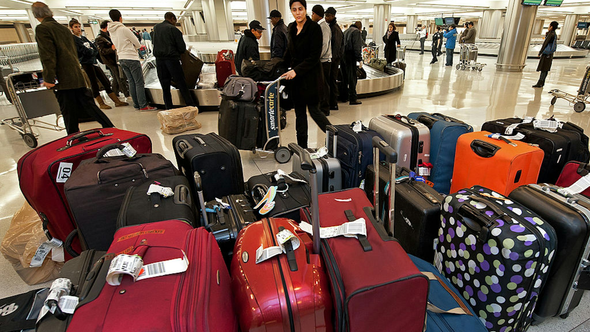 A woman pushes her luggage cart past unclaimed bags inside the US Customs and Border Protection inspection area at Dulles International Airport (IAD), December 21, 2011 in Sterling, Virgina, near Washington, DC.