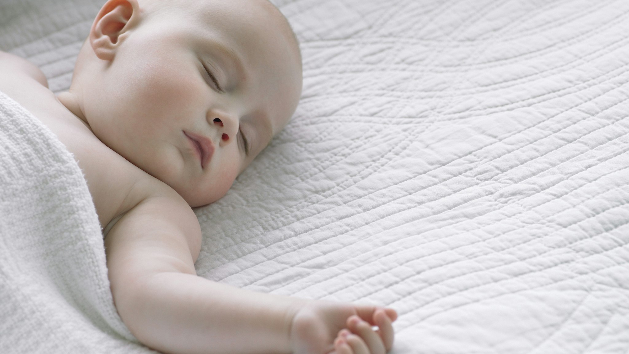 Baby girl (6-9 months) sleeping under blanket, close-up - stock photo